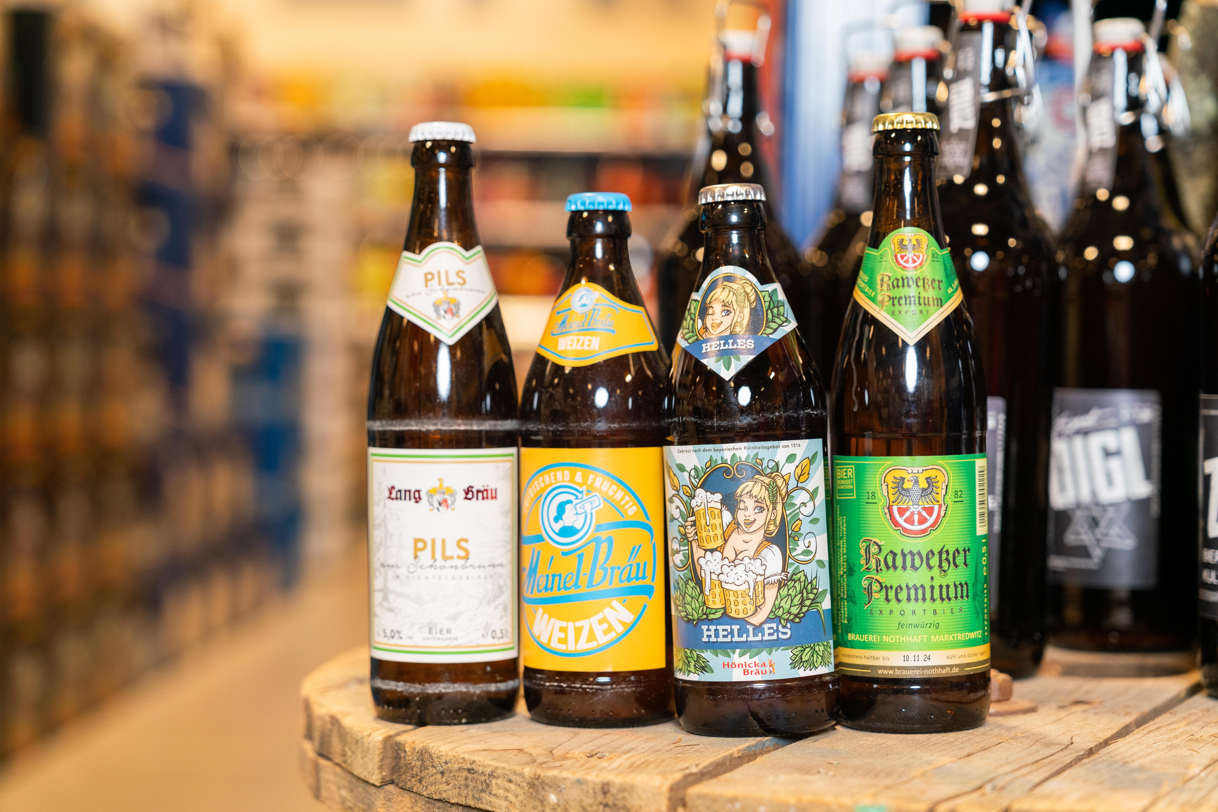 Vier verschiedene regionale Biere auf einem Holztisch.