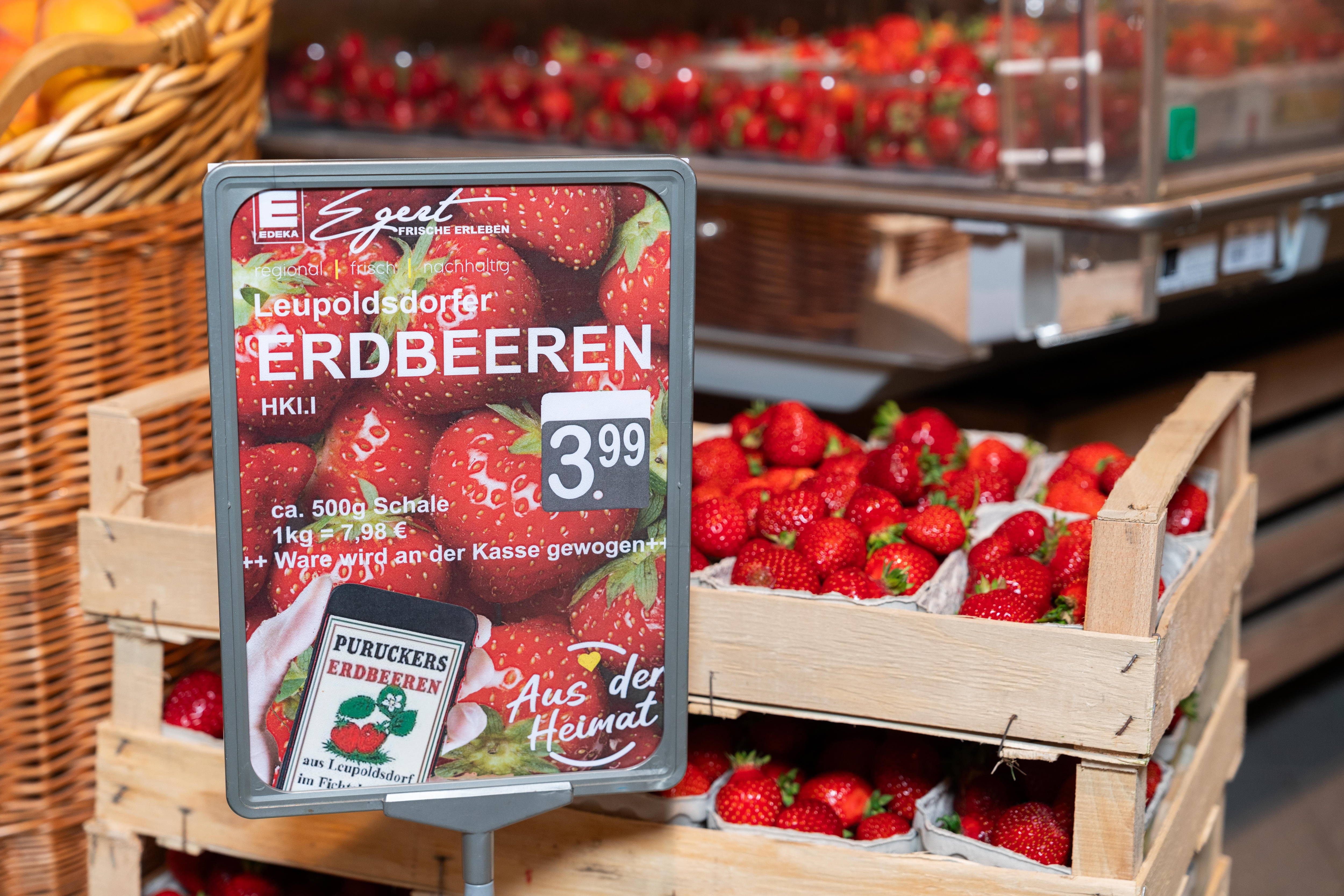 Holzkisten mit Schalen voller Erdbeeren.