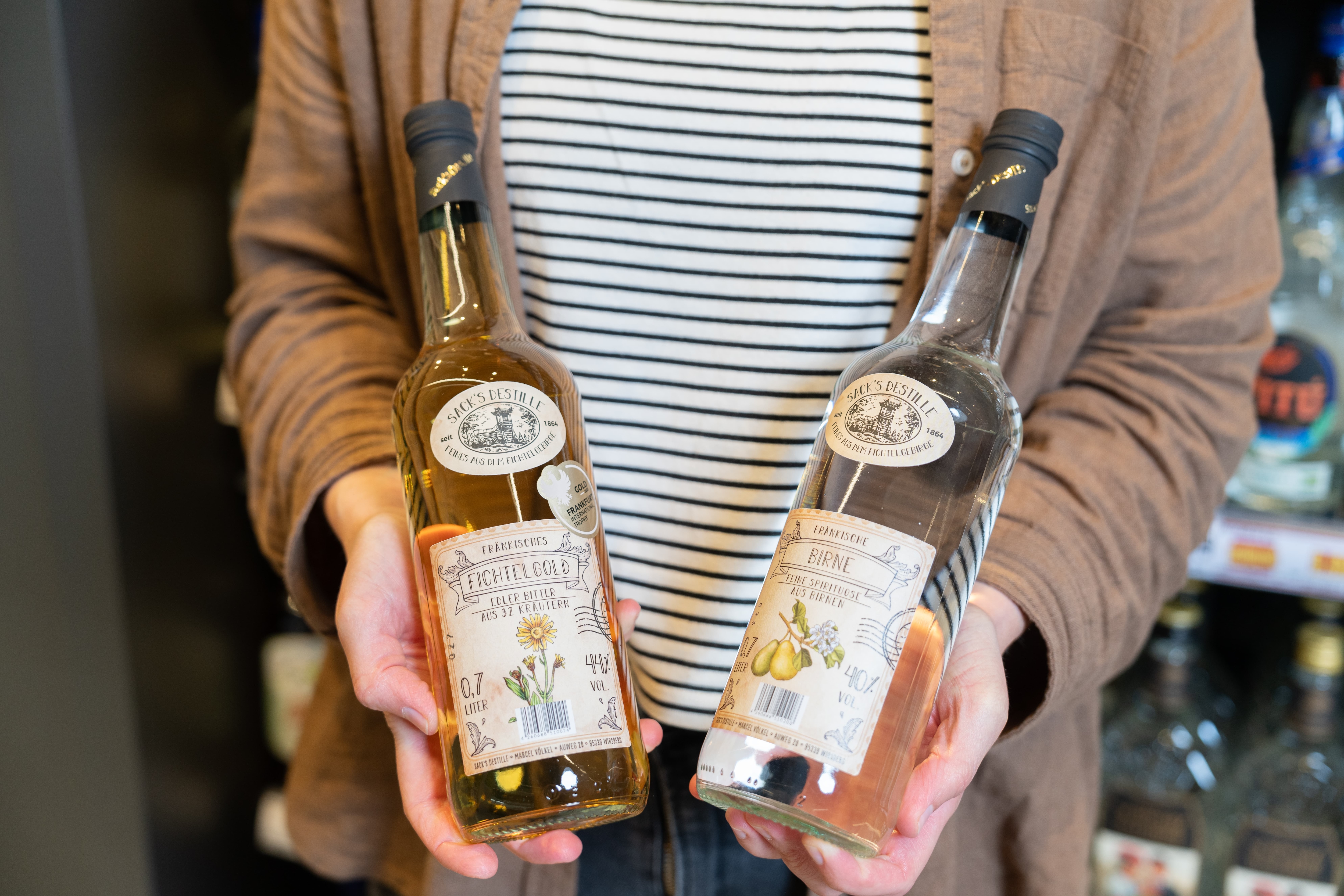 Nahaufnahme zweier Obstbrände in den Händen einer Person.