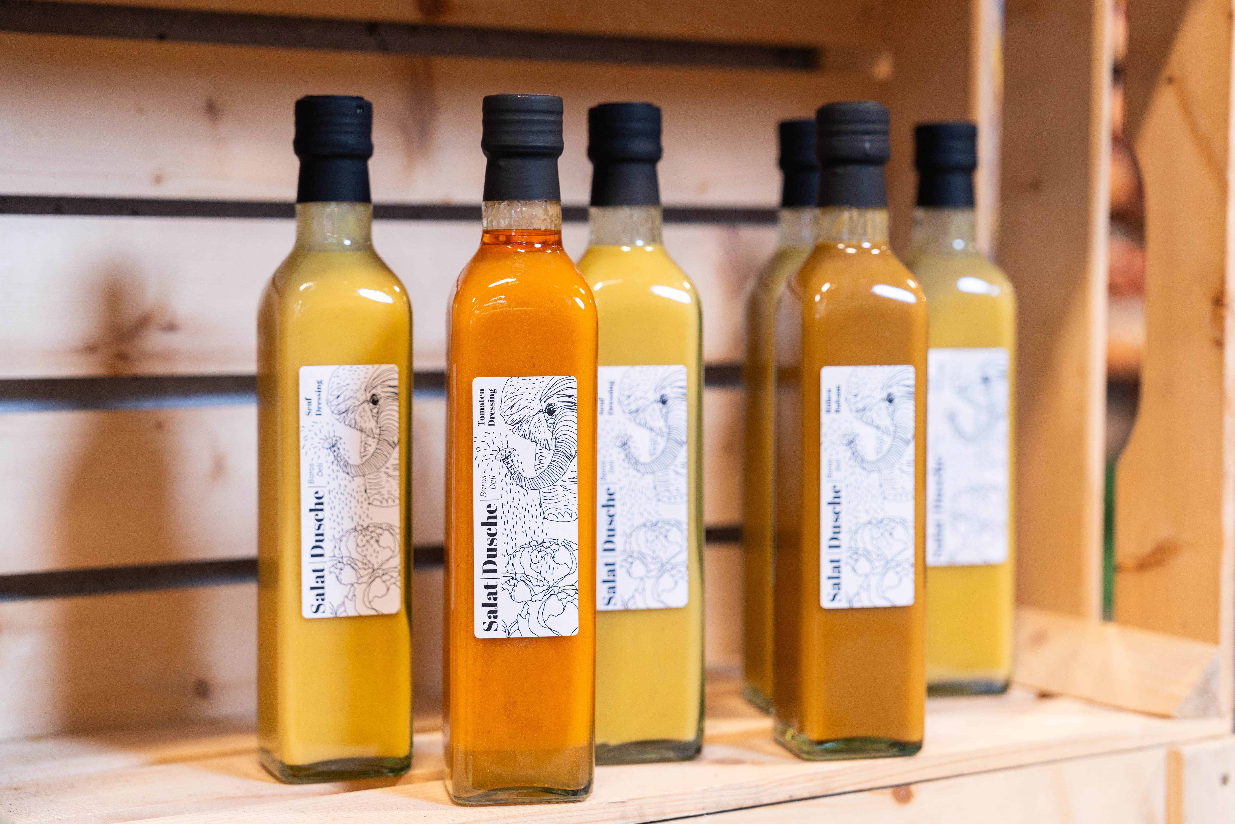Verschiedene Salatdressings in einem Holzregal.
