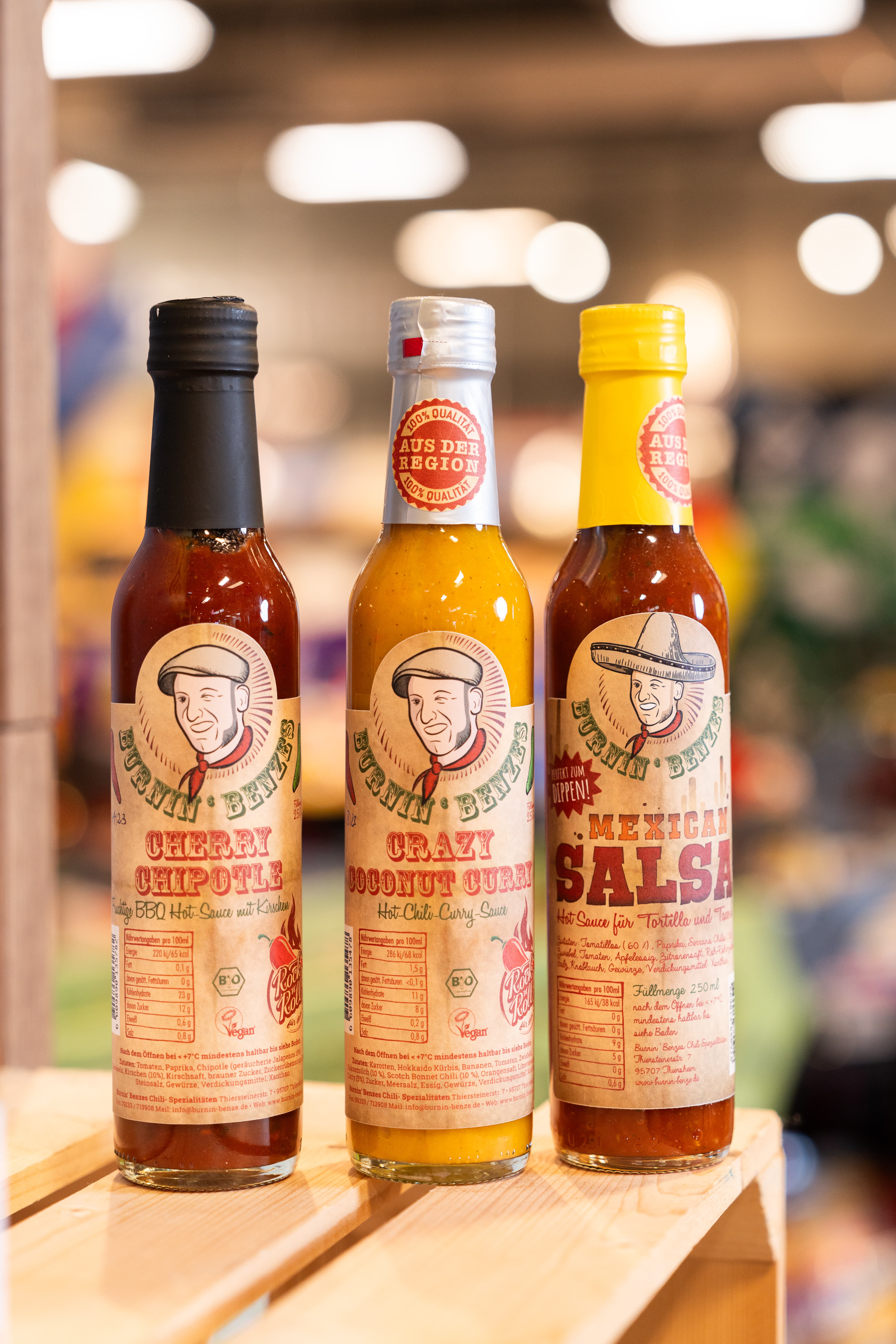 Verschiedene scharfe Saucen auf einer Holzkiste.