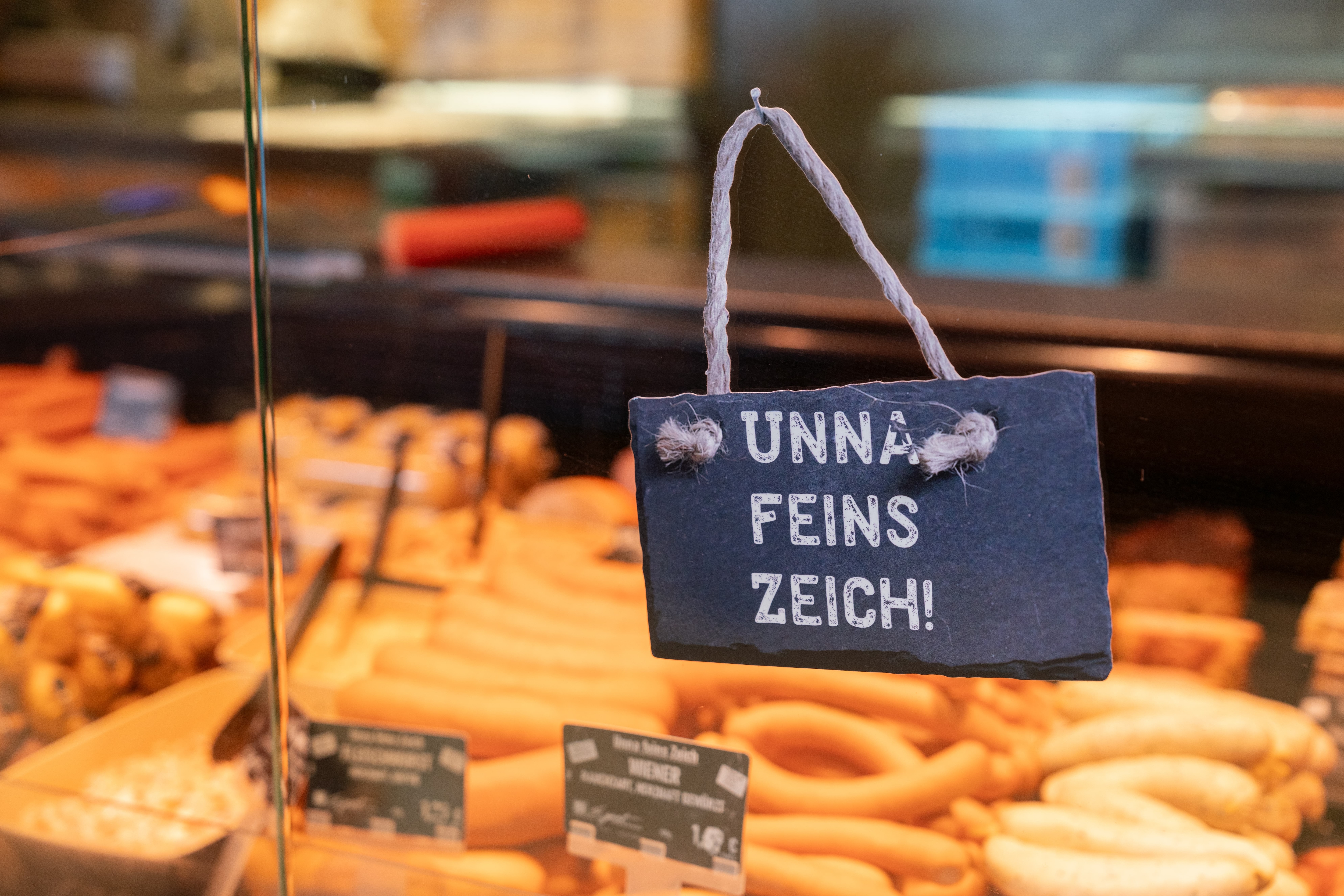 Ein Schild an der Fleischtheke eines EDEKA-Markts auf dem steht: "Unna feins Zeich!"