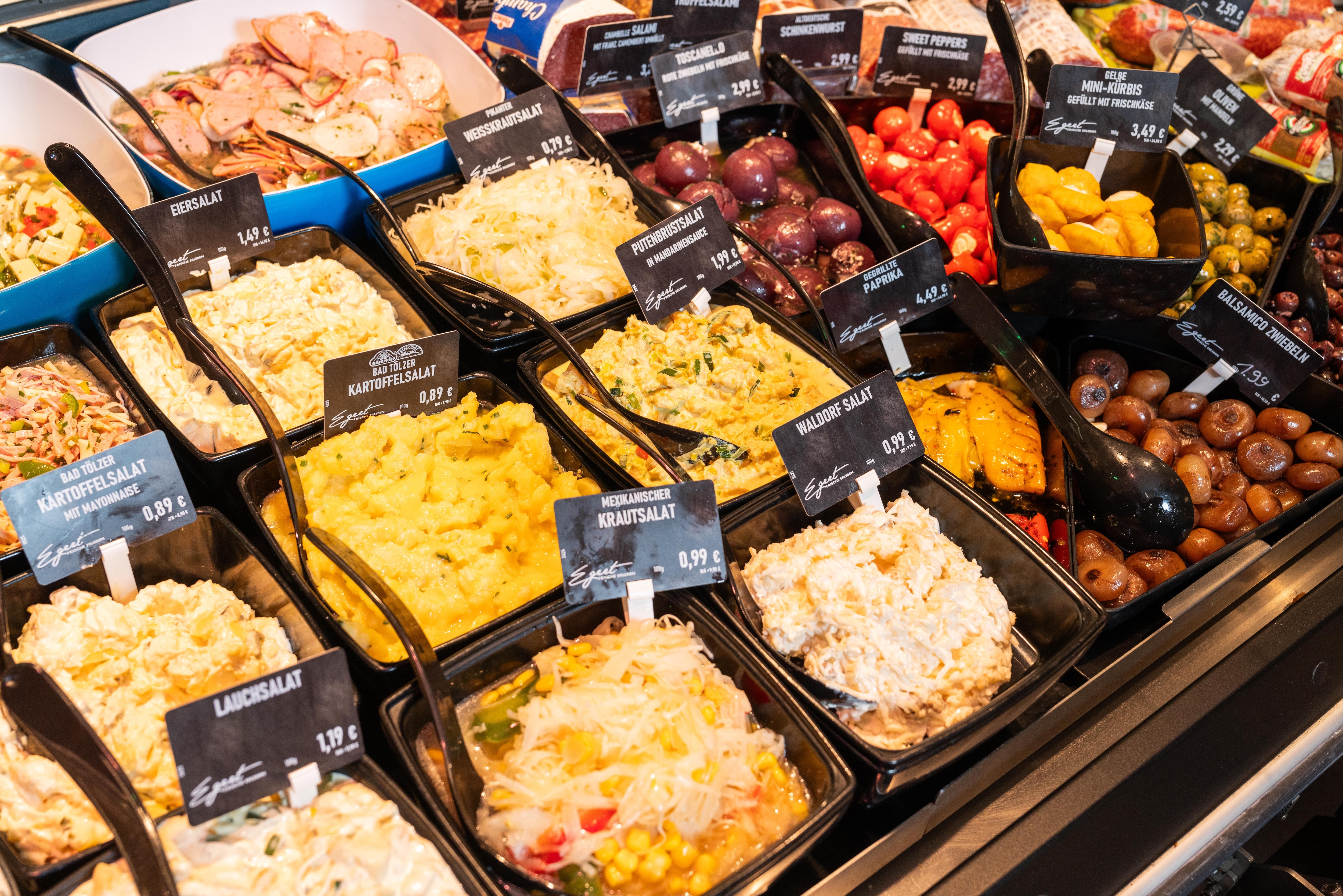 Verschieden Schüsseln mit Salaten und Antipasti in der Auslage einer Bedientheke.