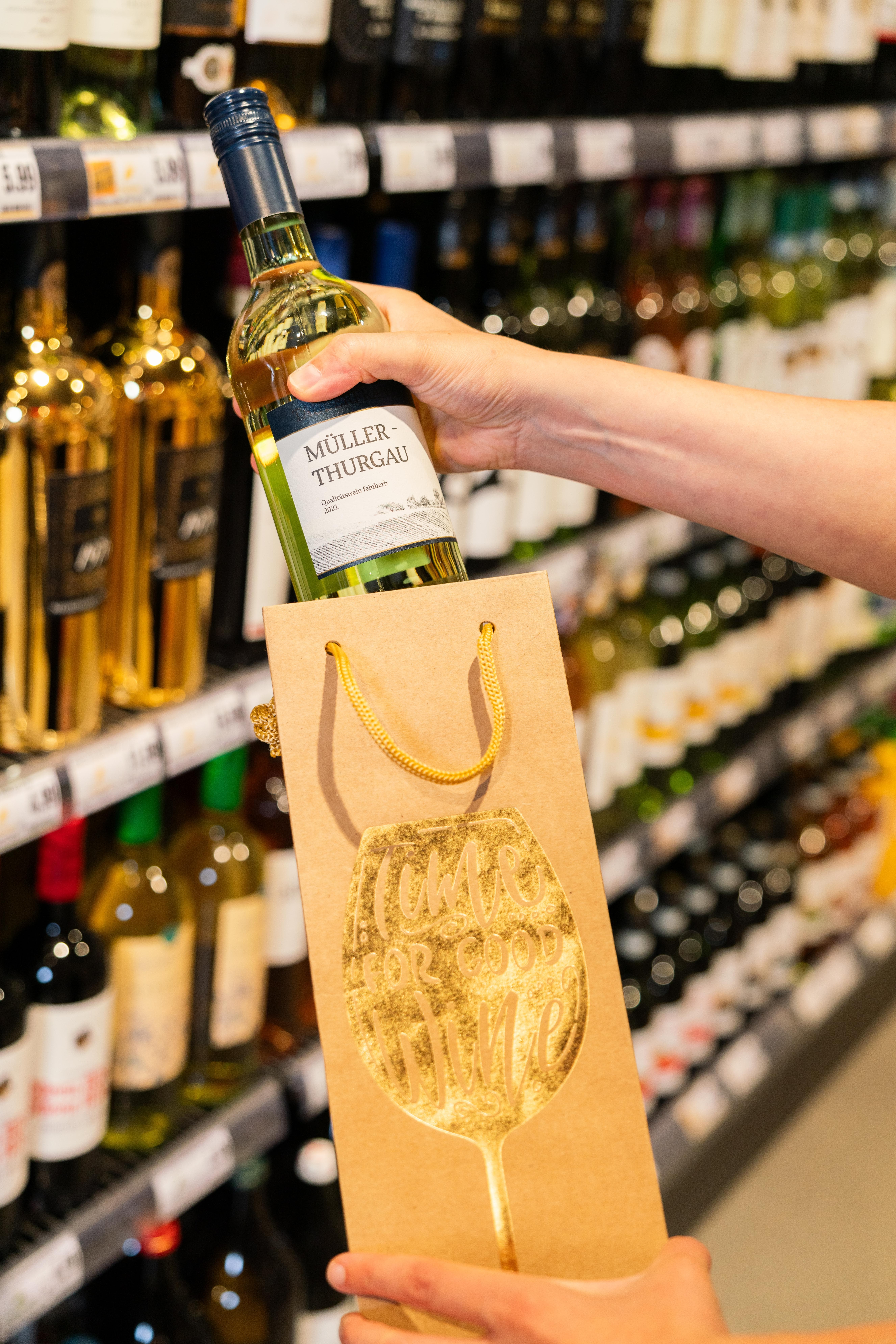 Eine Person steckt eine Flasche Wein in eine dafür vorgesehene Tüte.