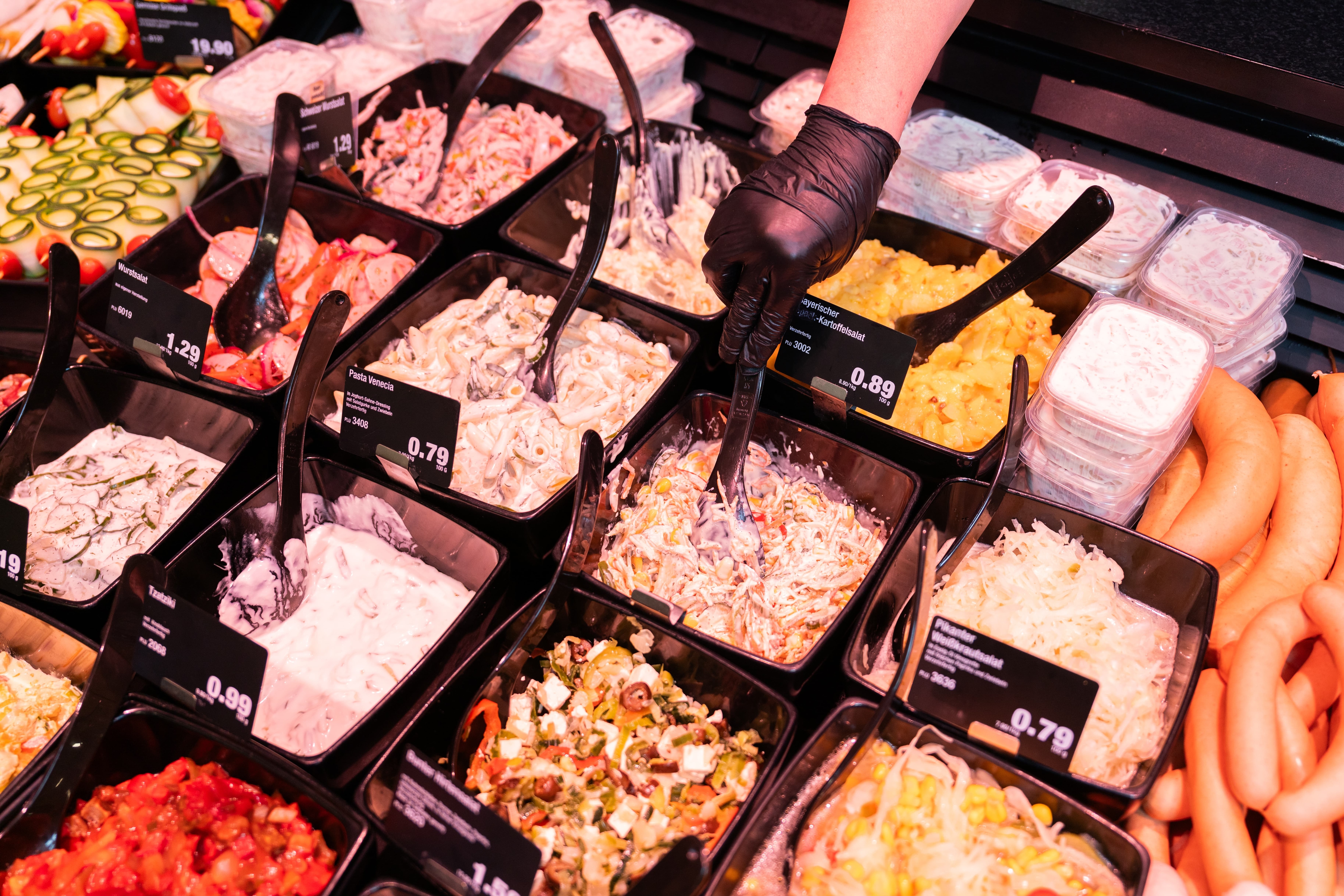 Die Auslage einer Frischetheke mit Schalen voller unterschiedlicher Salate.