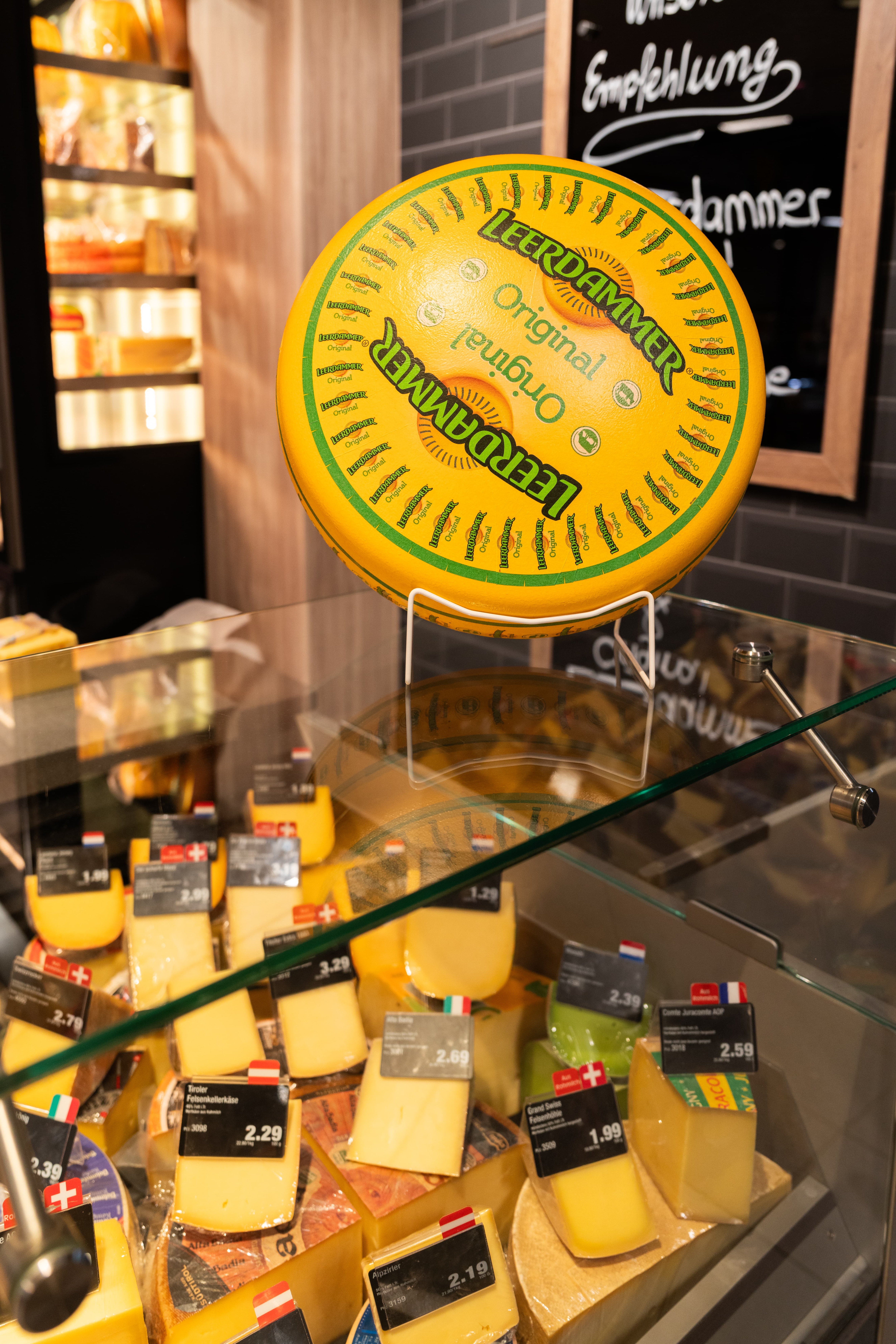 Ein Ausschnitt der Käsetheke eines EDEKA-Marktes. Auf dem Tresen steht ein Käserad.