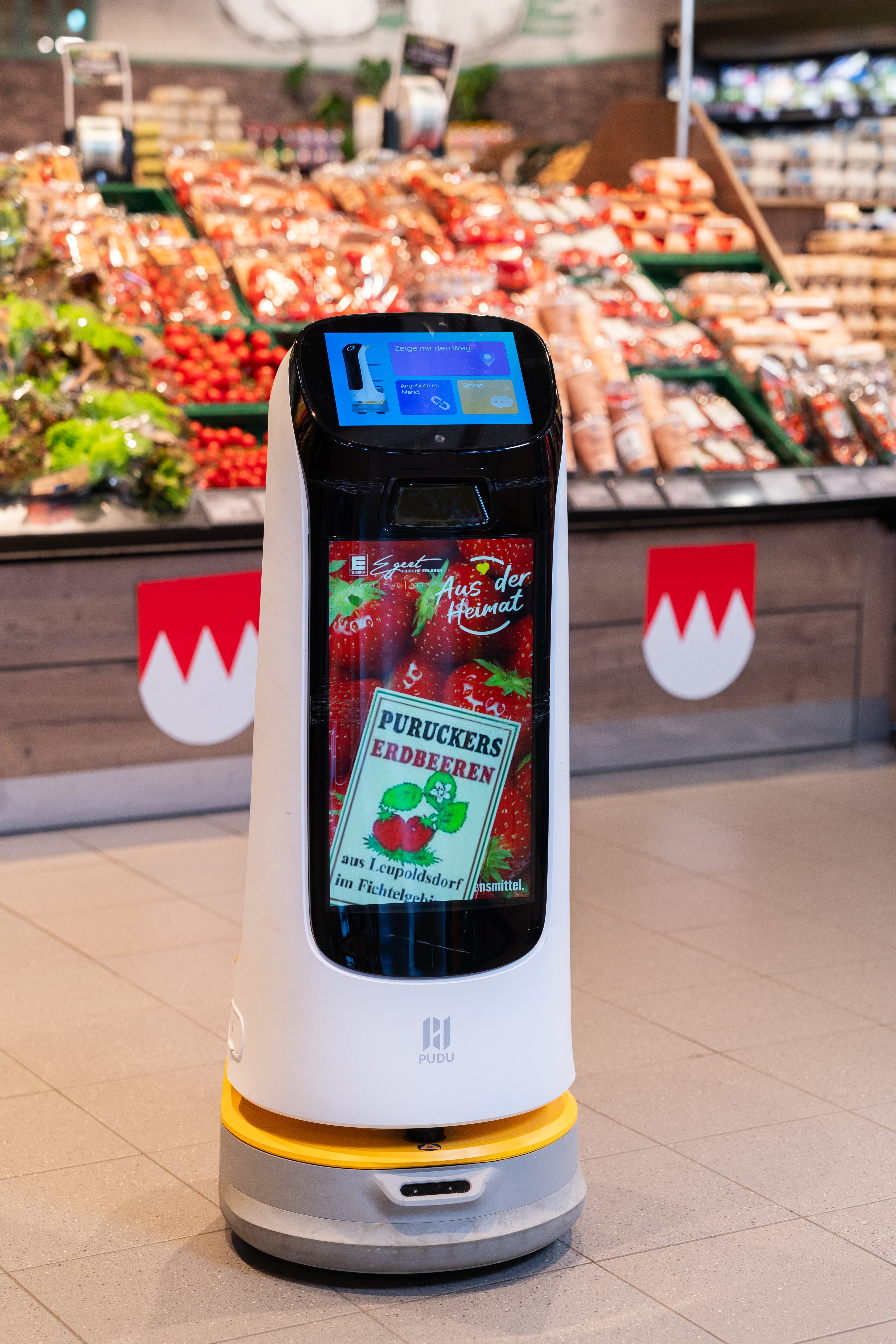 Ein Roboter mit Display in der Gemüseabteilung eines EDEKA-Marktes.