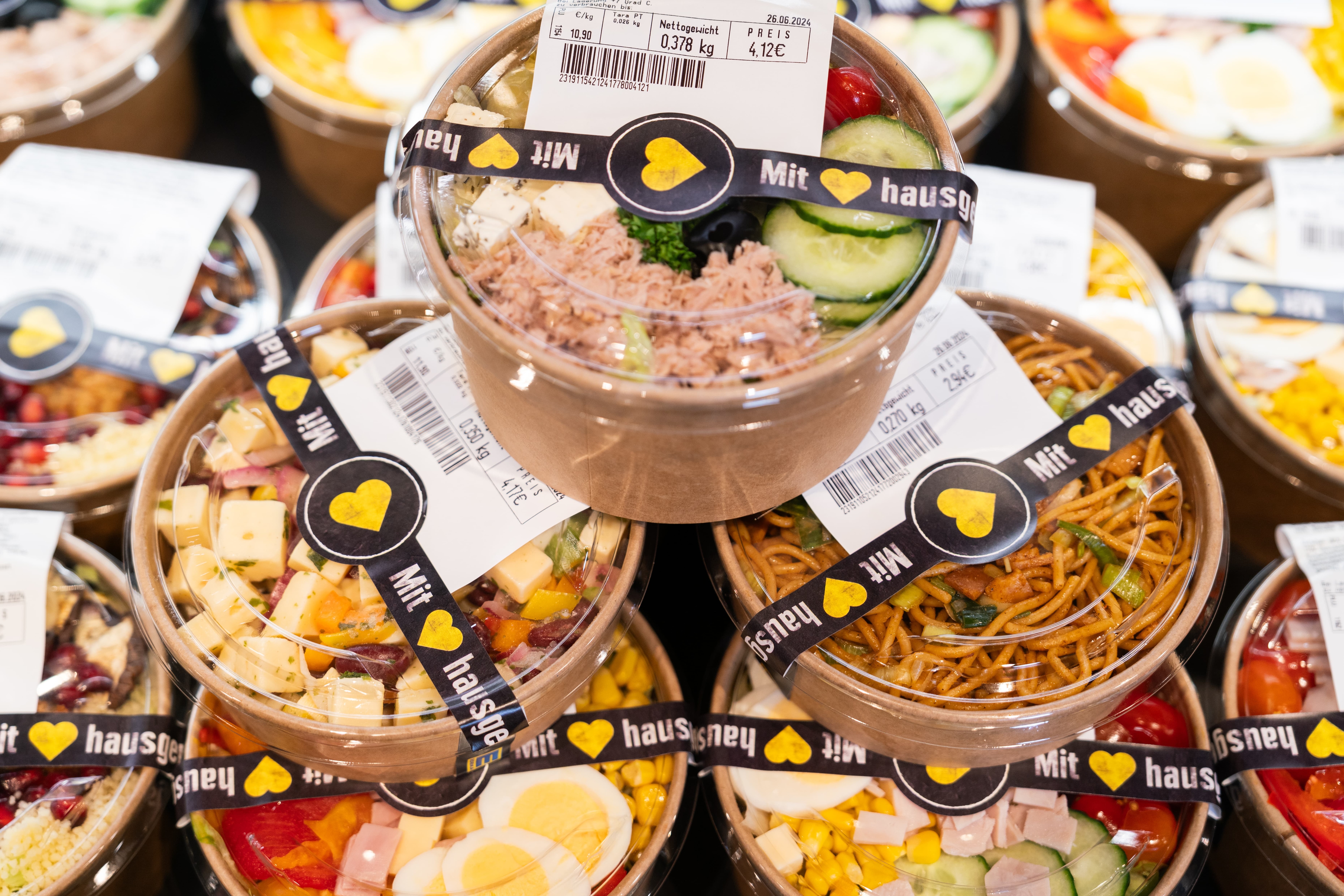 Verschiedene frische Salate in einer Pappschale mit Plastikdeckel.