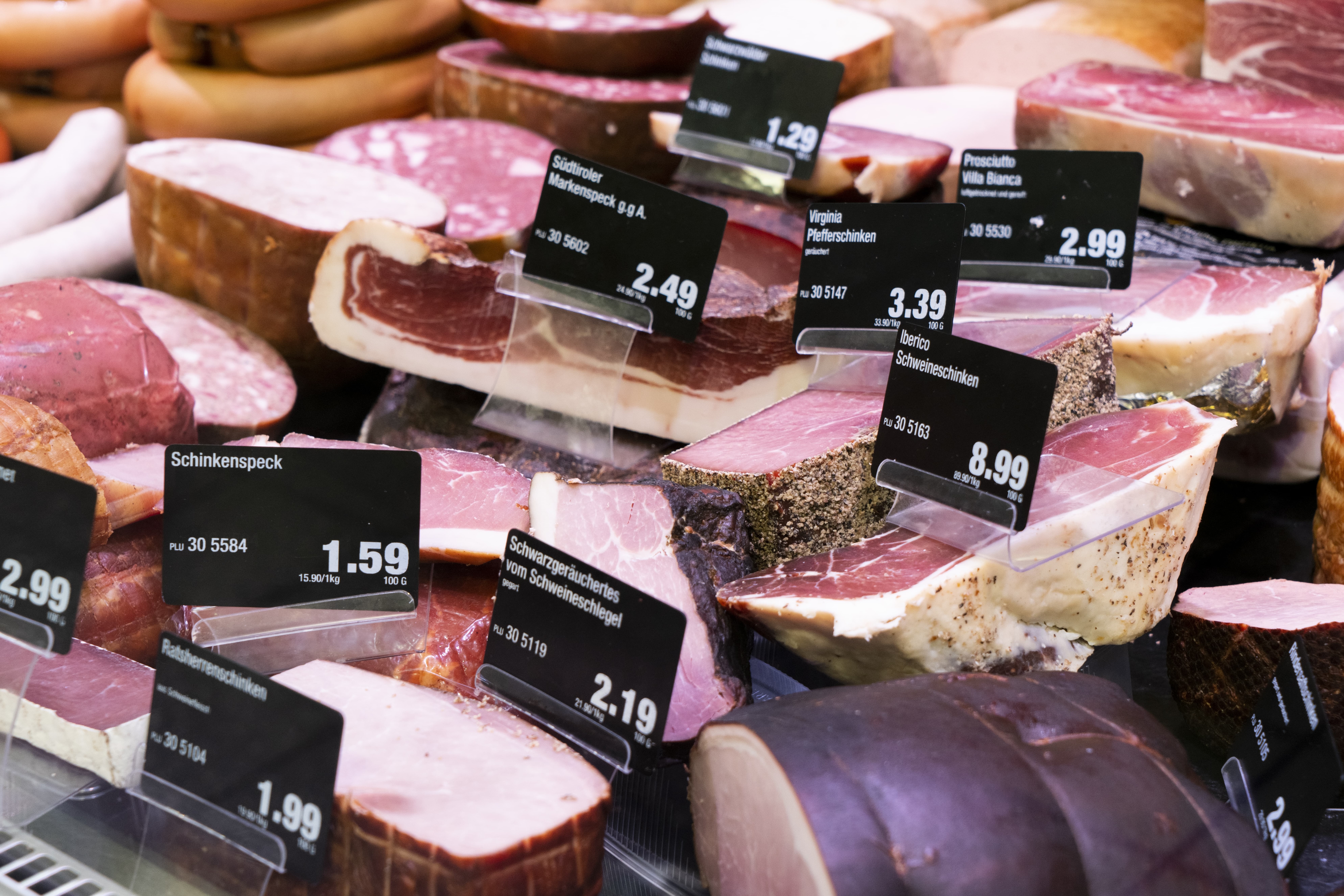Große Speck- und Schinkenstücke mit Preisschildern.
