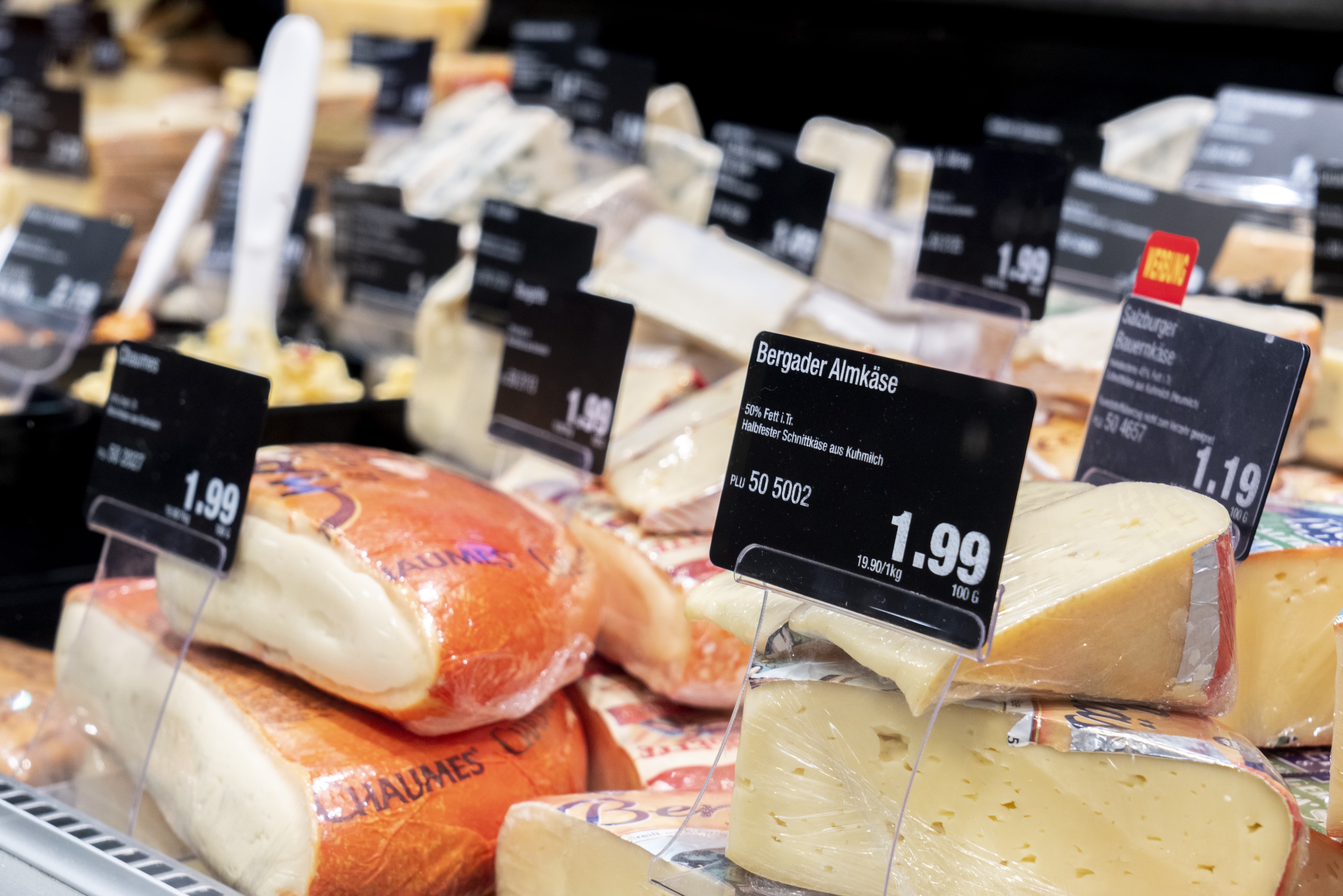 Verschiedene Käsesorten mit Preisschildern in einer Auslage.