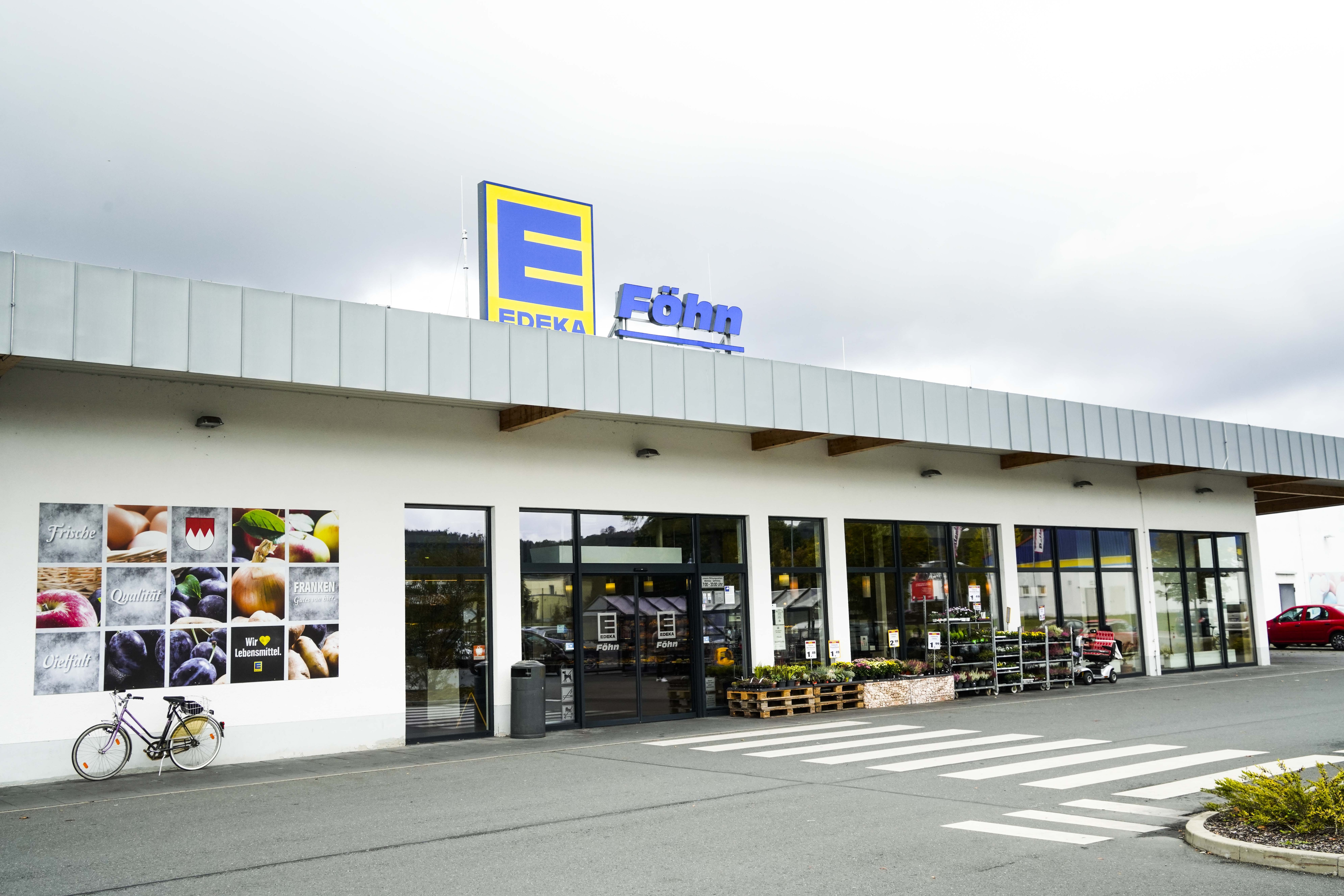 Front des Markts, bei regnerischem Wetter, mit dem Schriftzug EDEKA Föhn über dem Eingang.