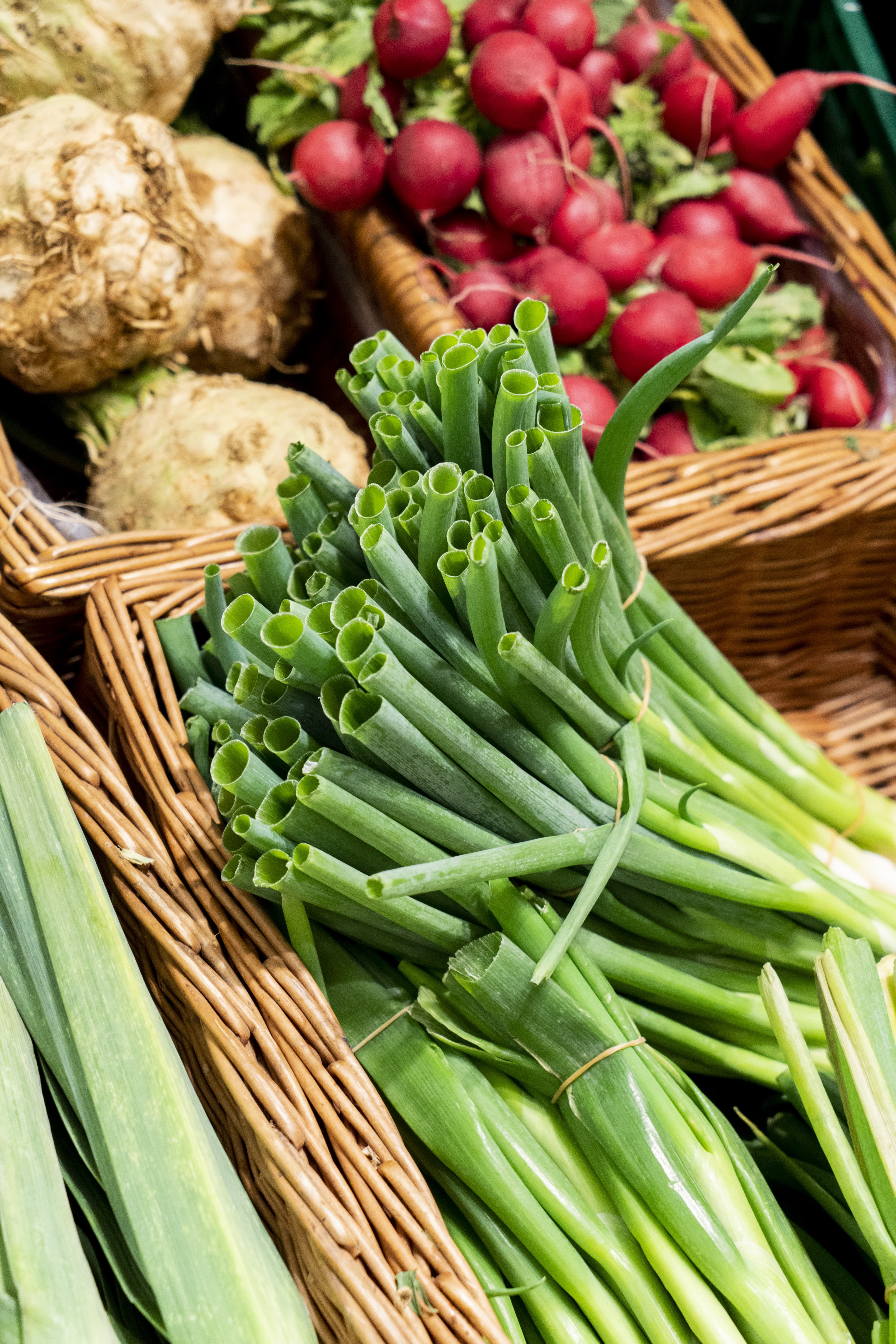 Close-Up verschiedener Gemüsesorten in einer Gemüseabteilung, im Vordergrund Frühlingszwiebeln.