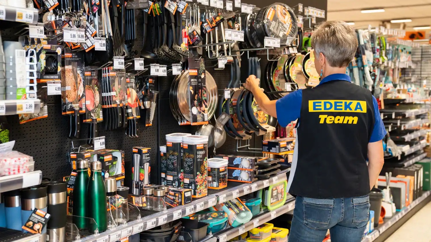 Eine Mitarbeiterin steht in der Haushaltsabteilung eines EDEKA-Marktes.