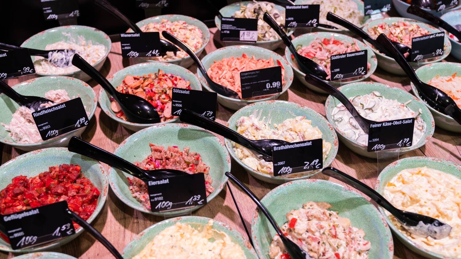 Schalen voller verschiedener Salate in der Auslage einer Frischetheke.