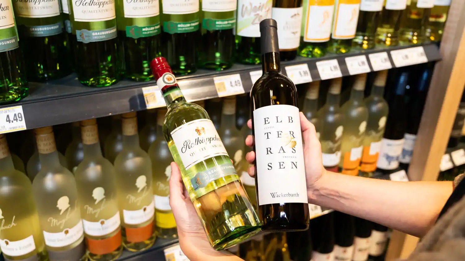 Eine Person hält jeweils eine Flasche Wein in jeder Hand.