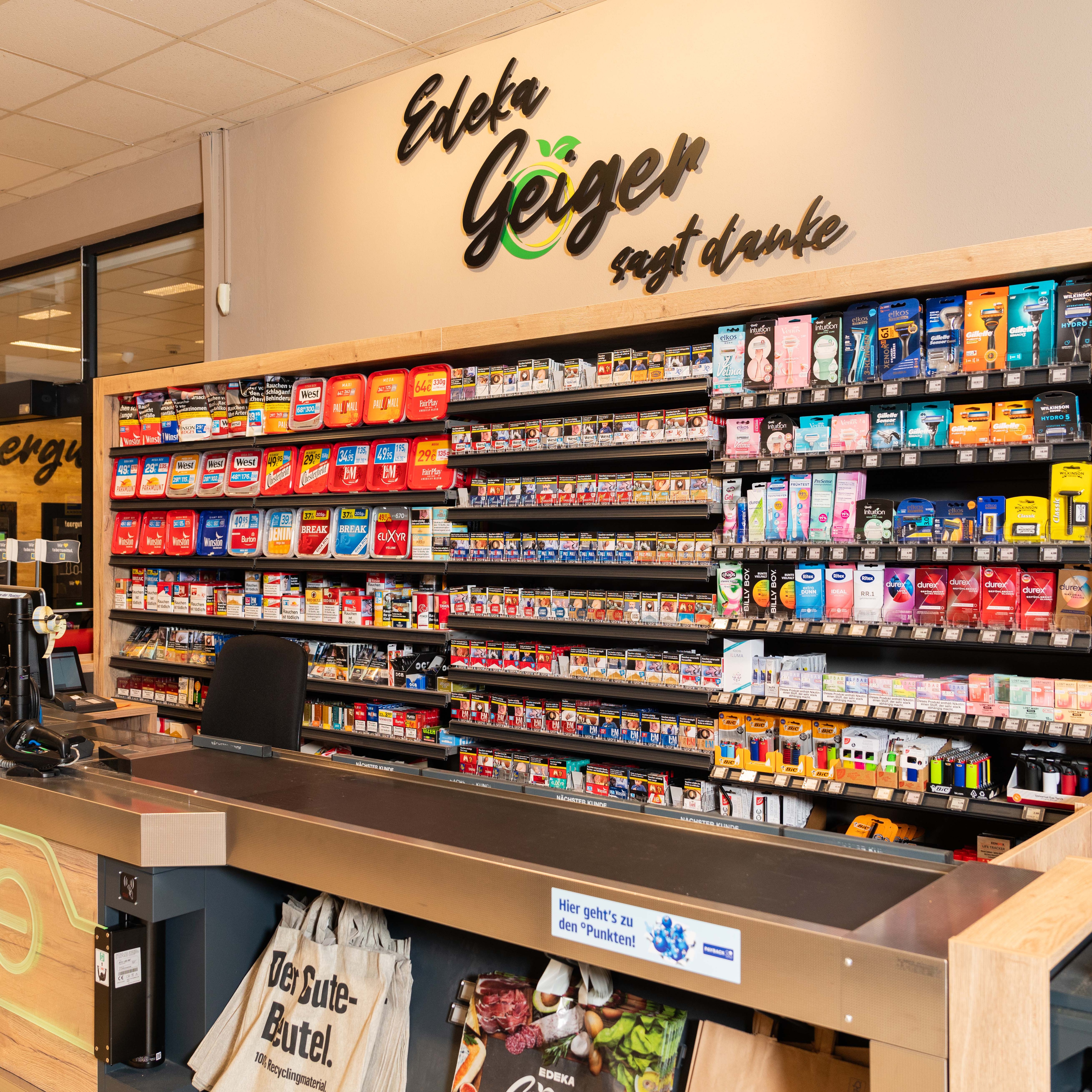 Blick auf einen Kassenbereich im Hintergrund sind Tabakwaren aufgereiht in einem Regal.