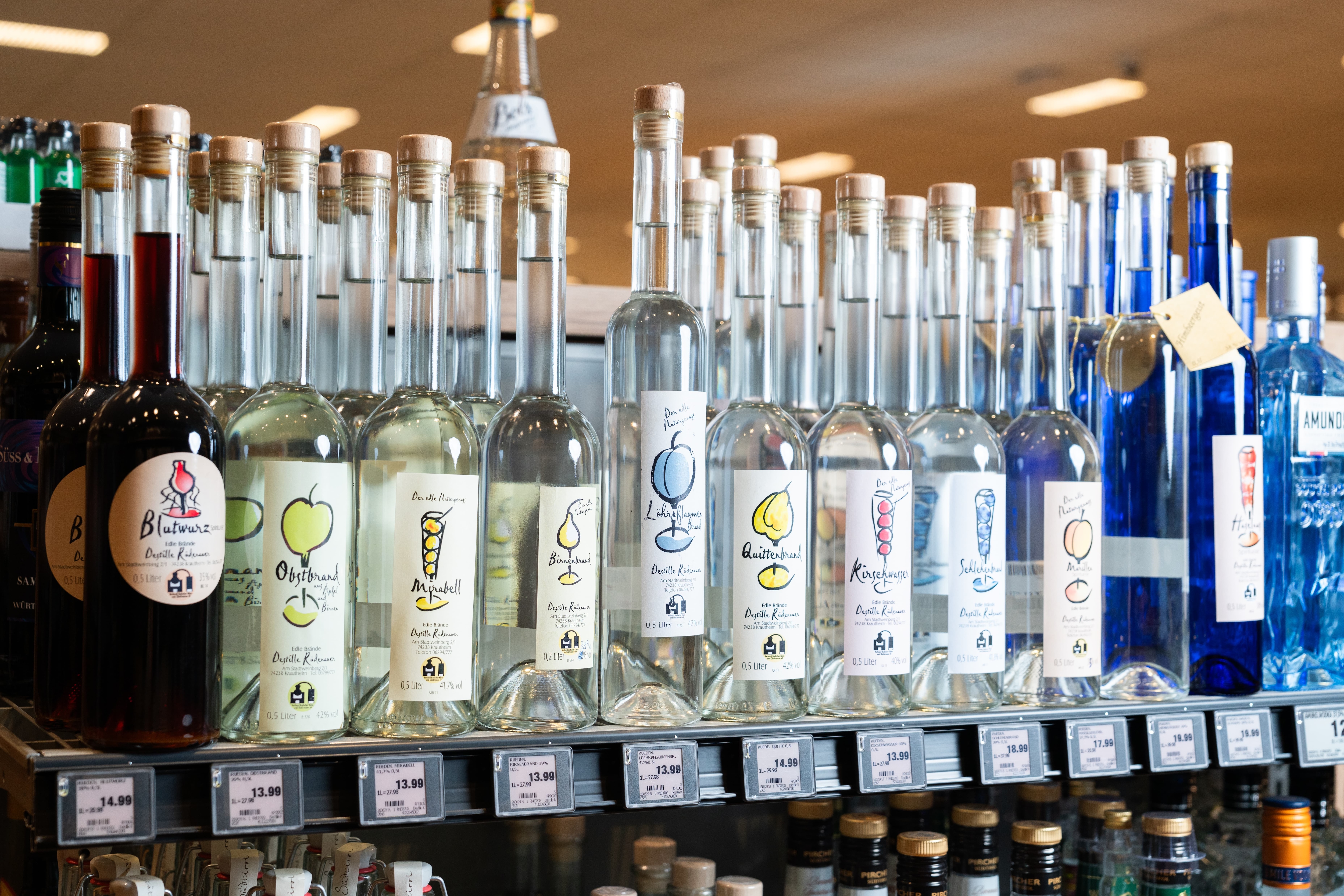 Nahaufnahme von unterschiedlichen Spirituosen aufgereiht in einem Regal.