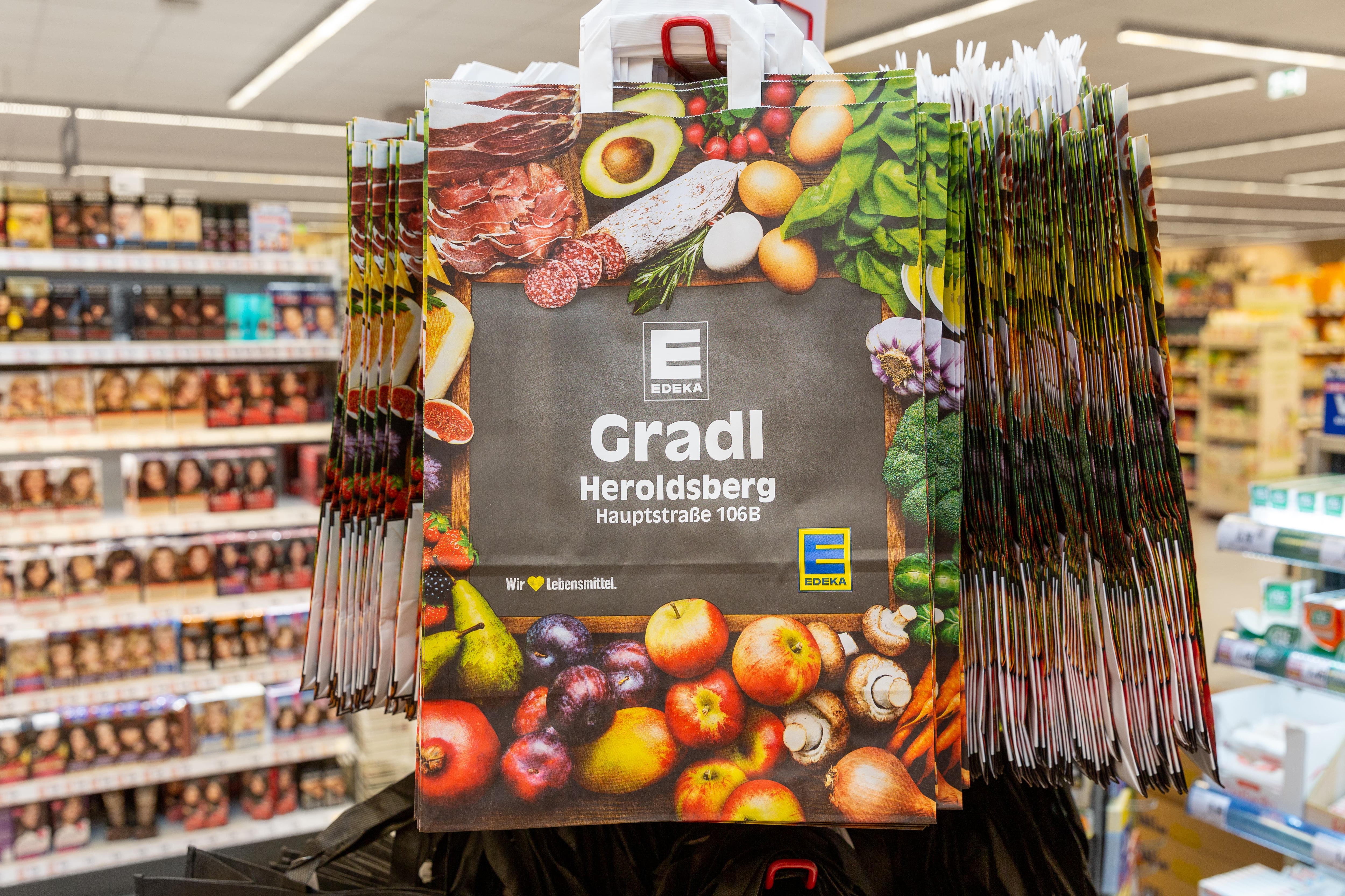Ein Ständer mit Mehrwegtragetaschen im Edeka-Design.