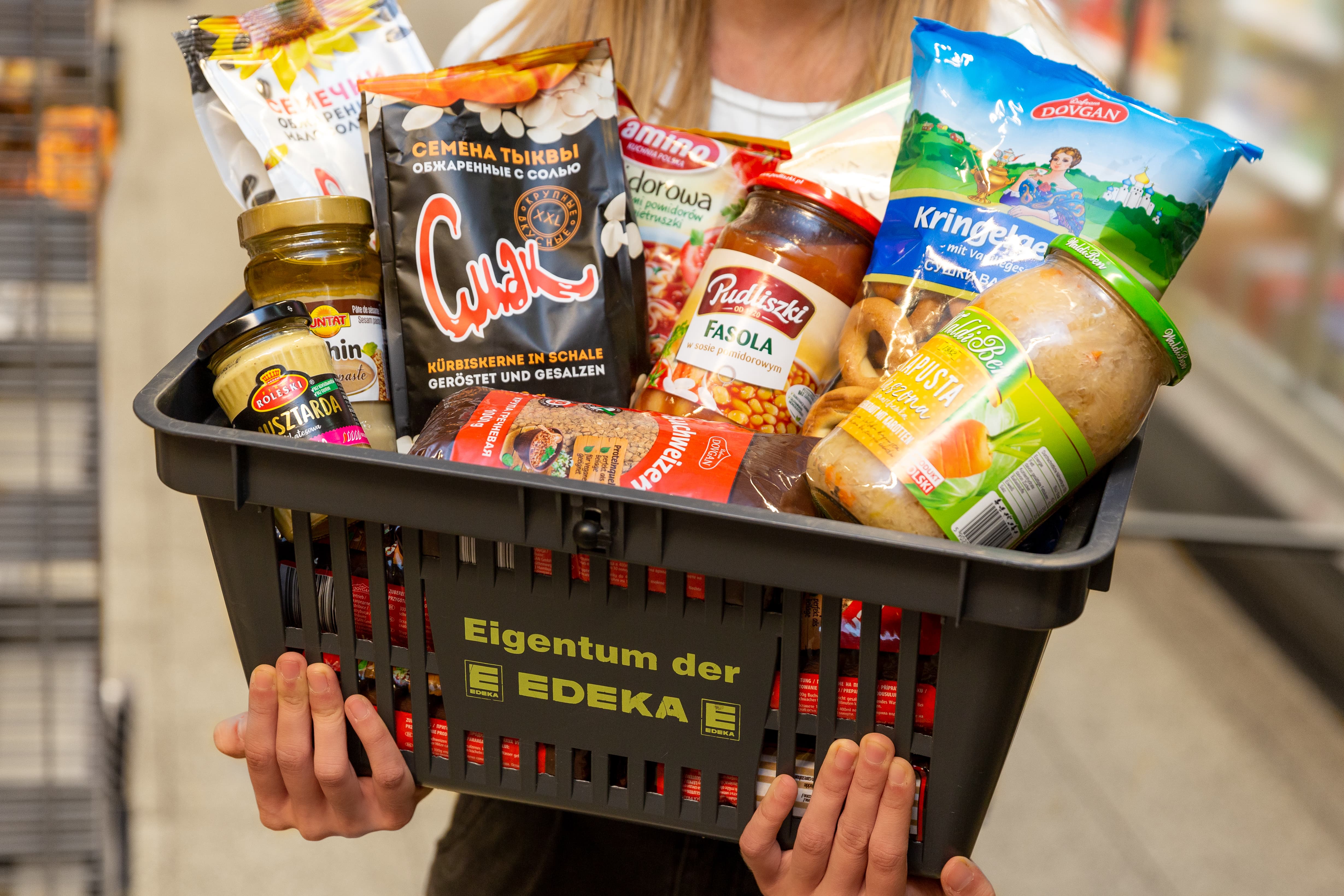 Junge Frau hält einen Korb gefüllt mit internationalen Spezialitäten.