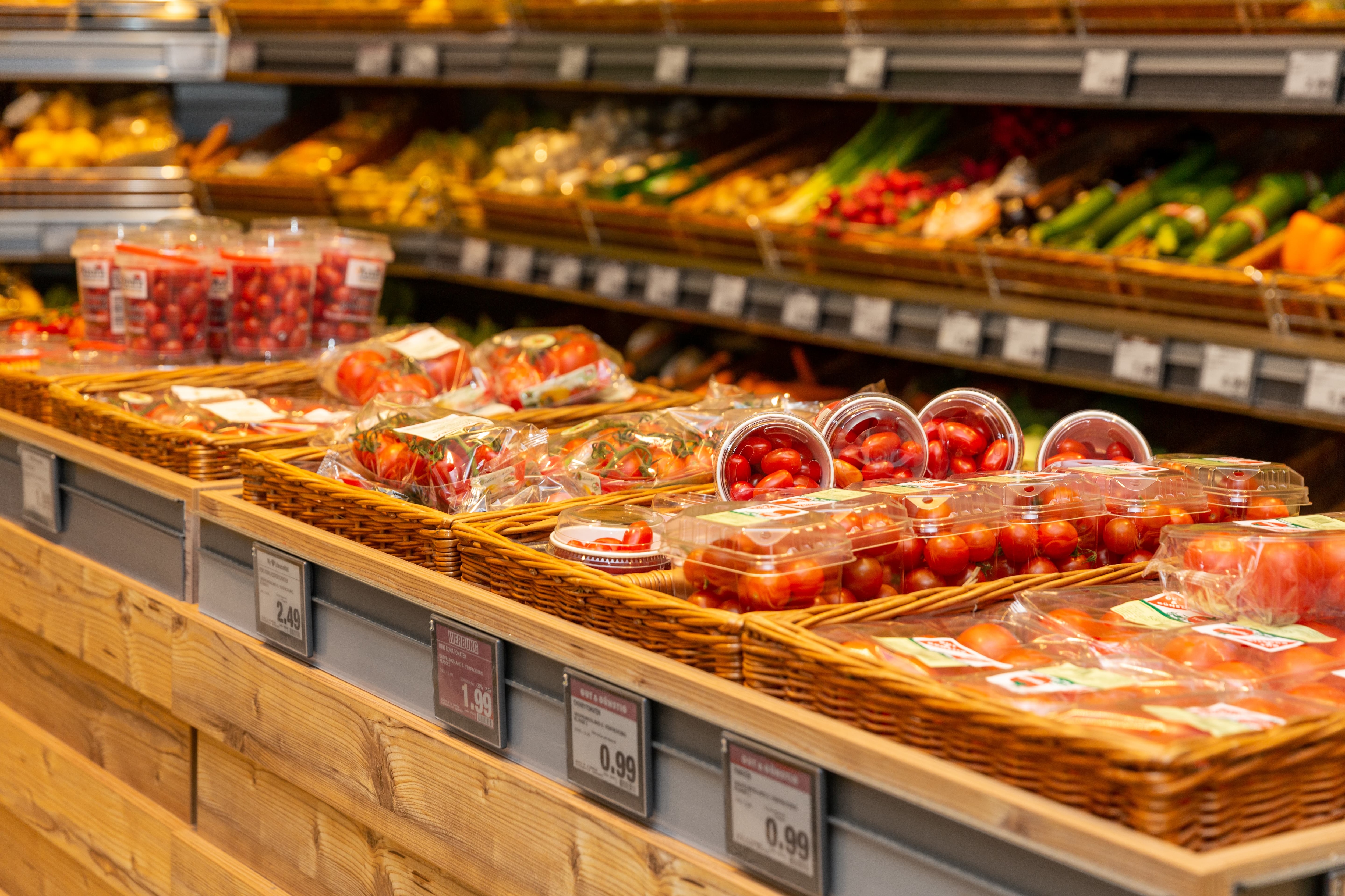 Körbe mit verschiedenen Tomatensorten in der Obst- und Gemüseabteilung eines Edeka-Marktes.