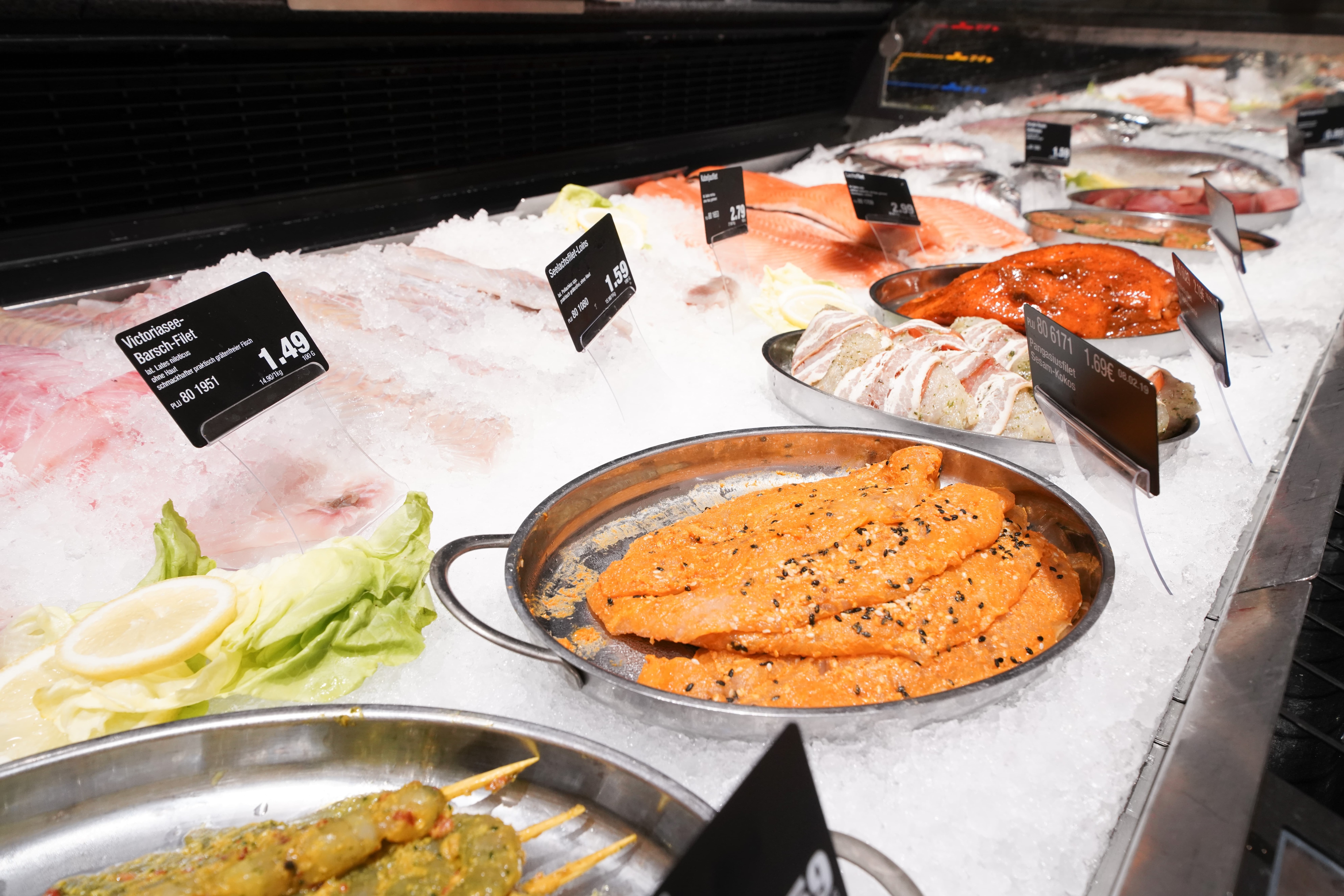 Fisch in einer Auslage, mit Preisschildern und frischer Dekoration.