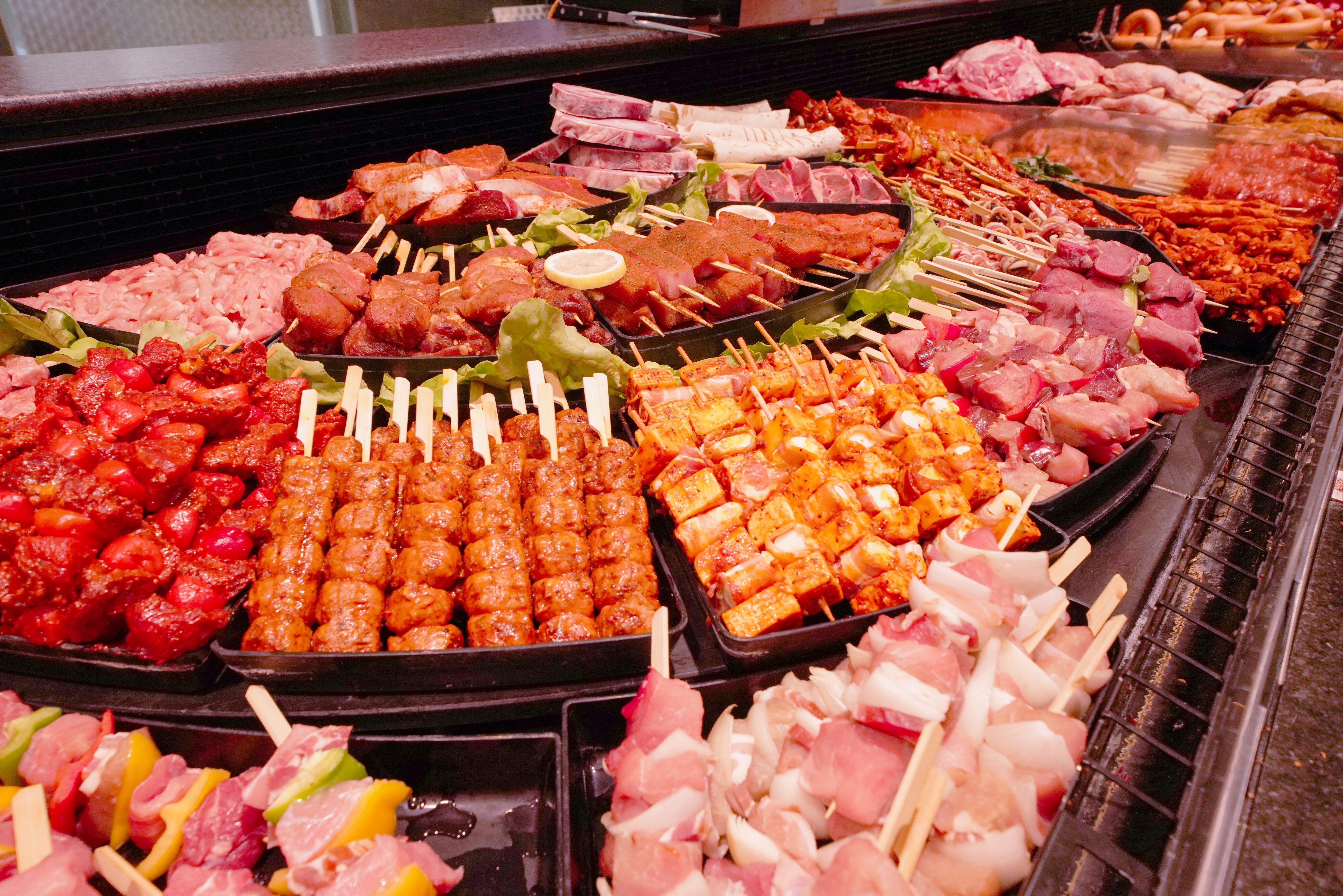 Die Fleischtheke eines EDEKA-Markts, mit vielen verschiedenen Produkten und Spießen.