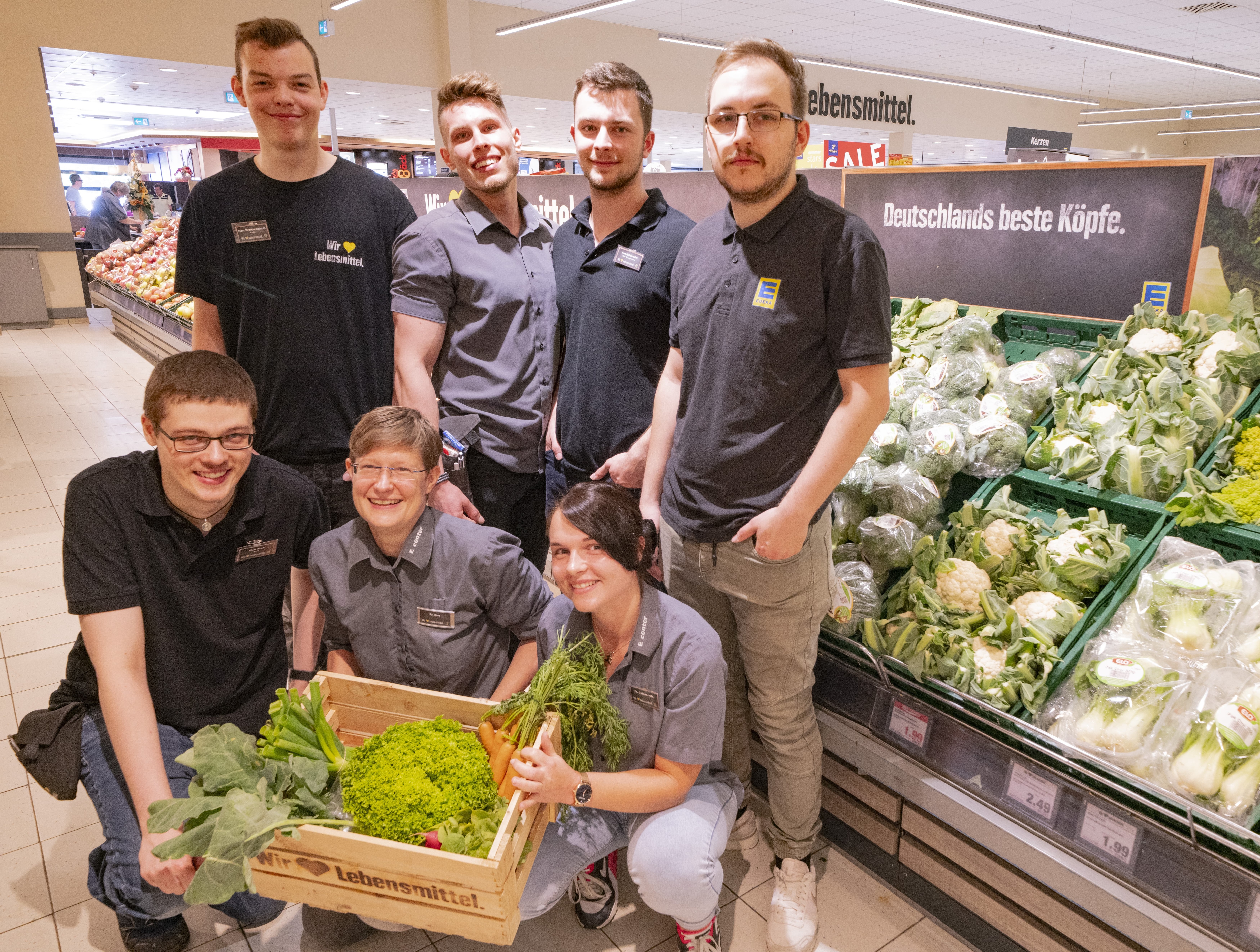 Gruppenfoto des Teams dieses EDEKA-Markts, aufgenommen in der Obst- und Gemüseabteilung.