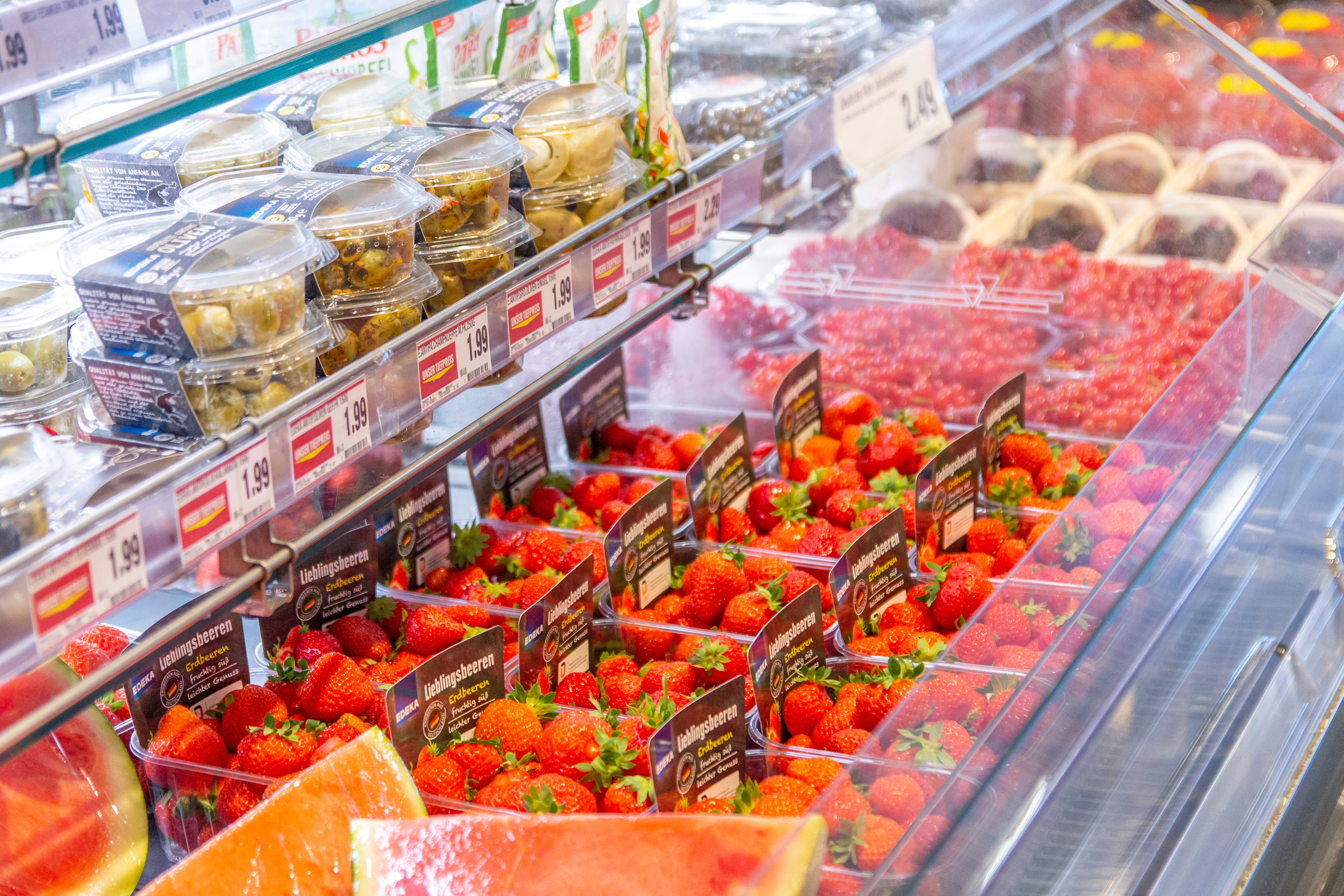 Viele Erdbeerschachteln in der Kühltheke einer Obstabteilung.