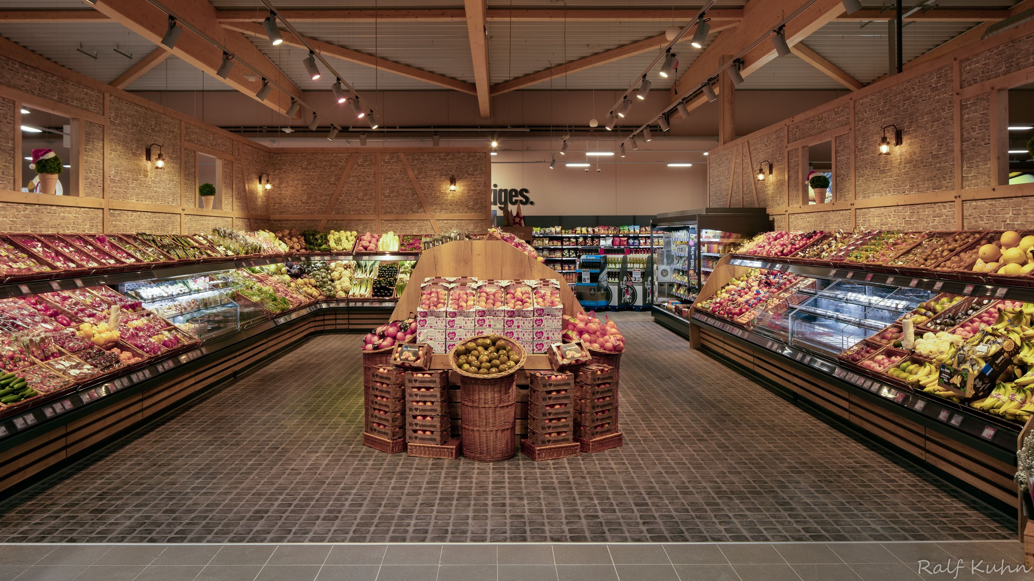 Man sieht die gesamte Obst- und Gemüseabteilung, die im Fachwerkstil an den Wänden gehalten ist.