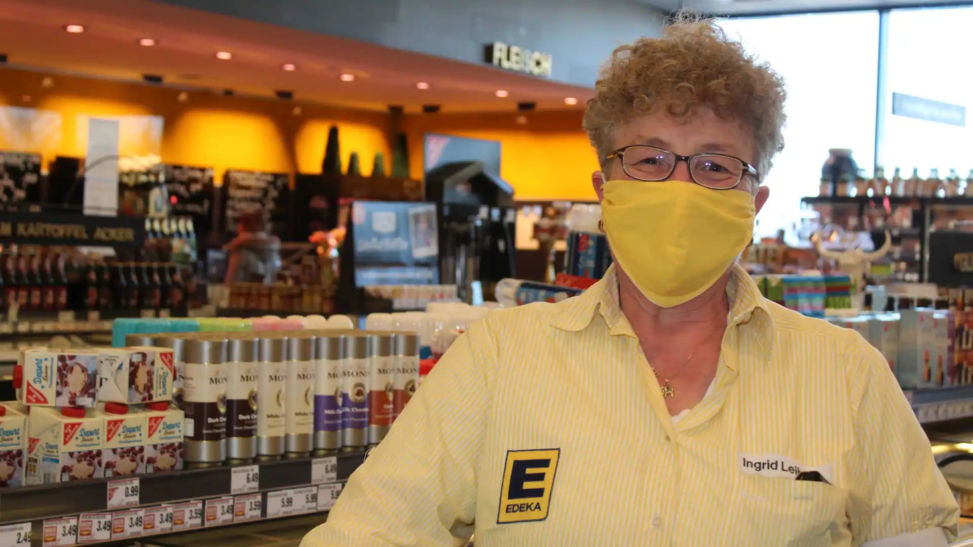 Eine Mitarbeiterin eines EDEKA-Marktes mit Maske.