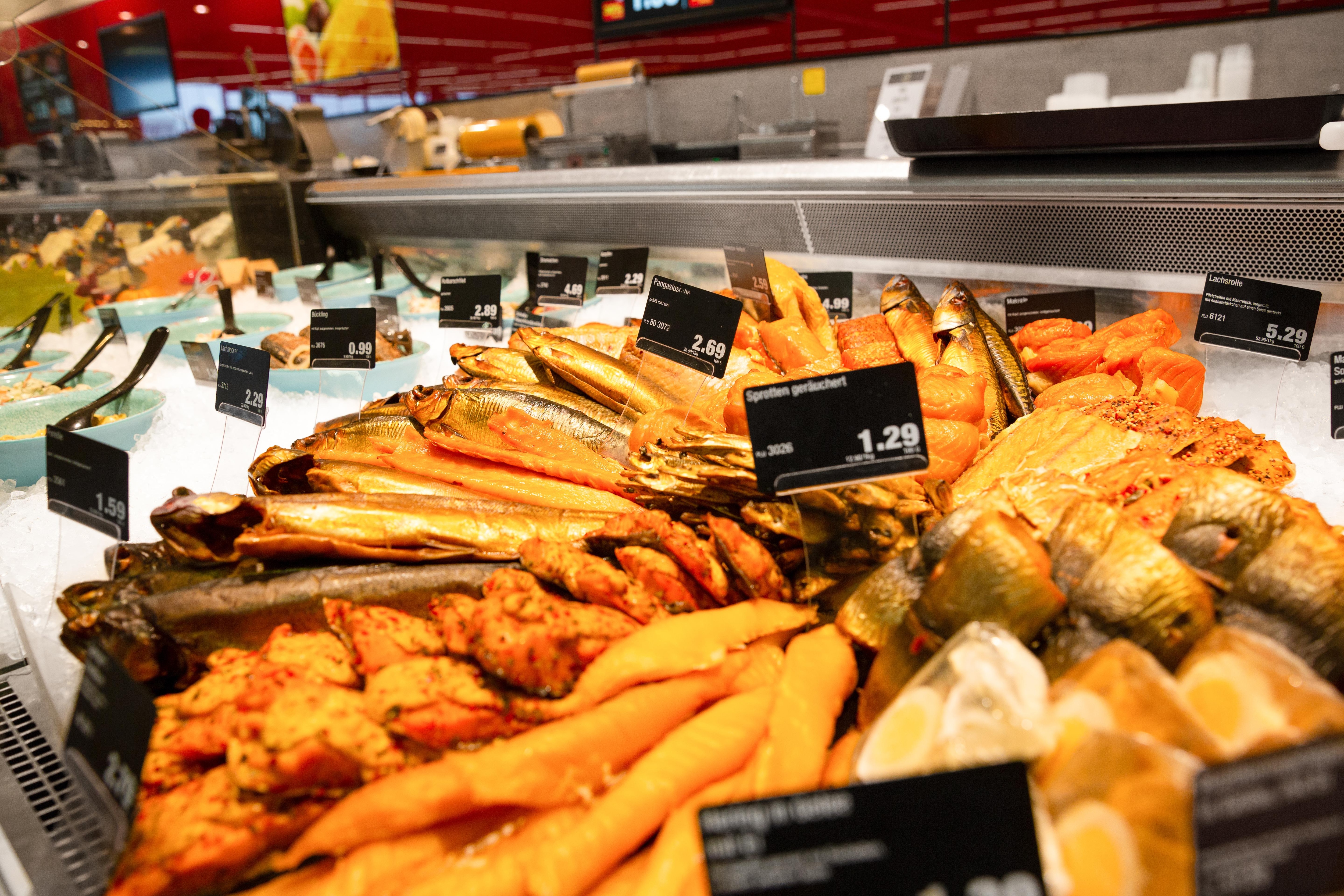 Verschiedene Fischspezialitäten mit Preisschildern versehen in der Frischetheke eines Edeka-Marktes.