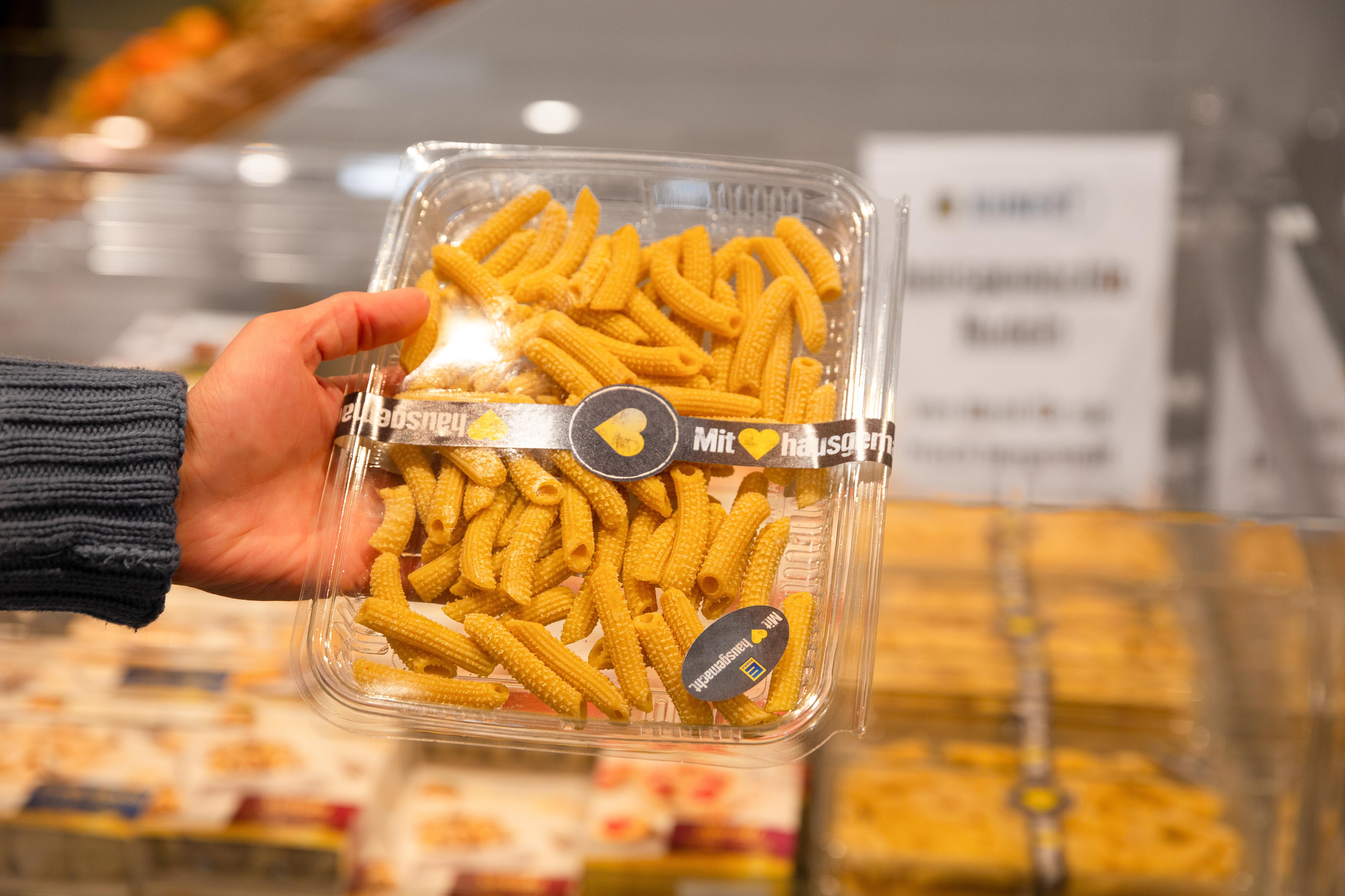Eine Hand hält eine Packung mit hausgemachter Pasta von Edeka.