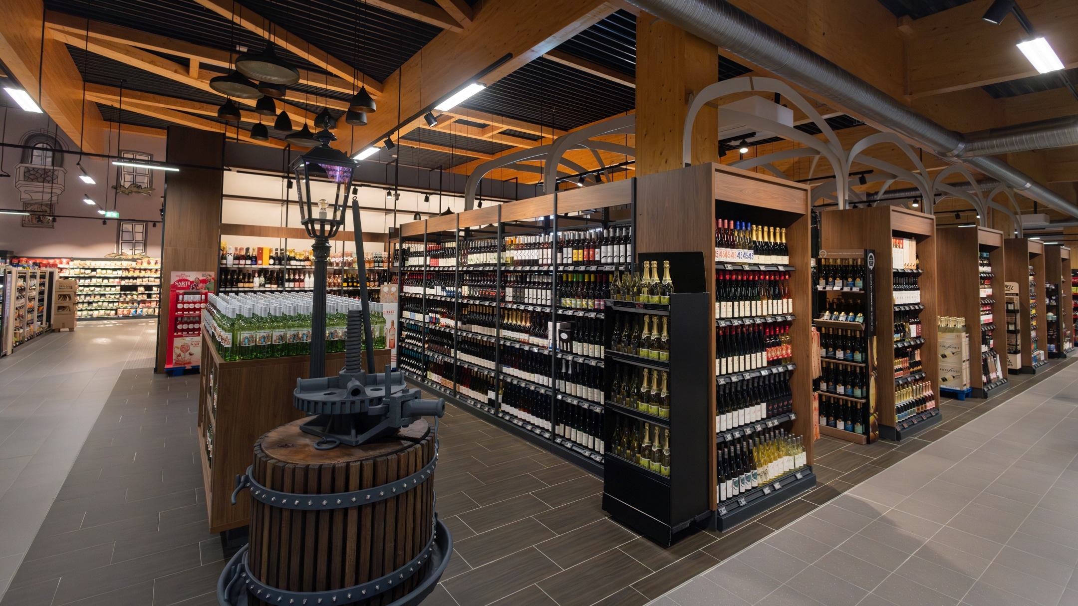 Regalansicht der Wein- und Sektabteilung mit einer Weinpresse als Dekoration im Vordergrund