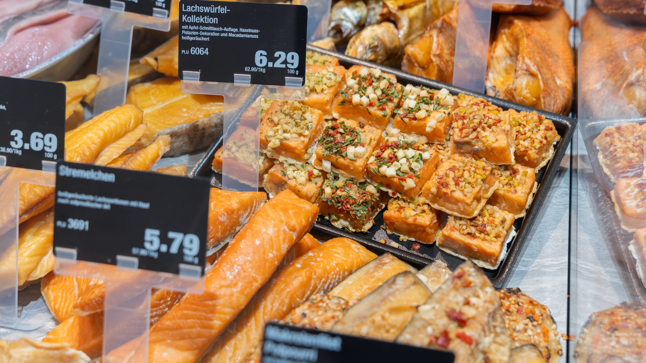 Ein Ausschnitt der Fisch-Frischetheke mit Angeboten für eine Lachswürfel-Kollektion, Stremelchen und Makrelenfilets