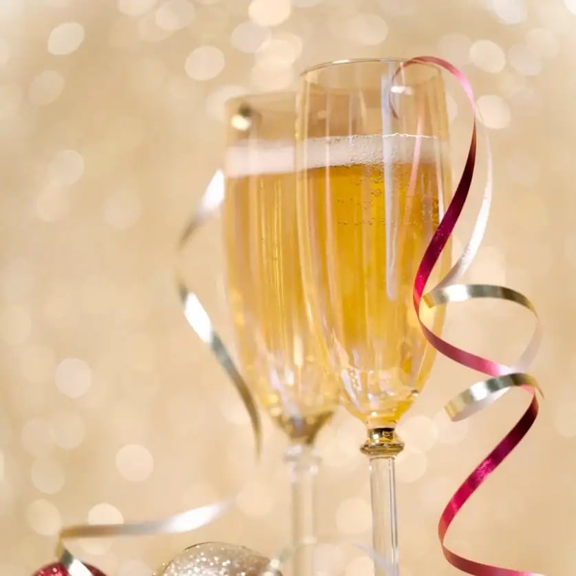 Zwei Gläser mit Champagner auf denen ein glitzerndes Band liegt.