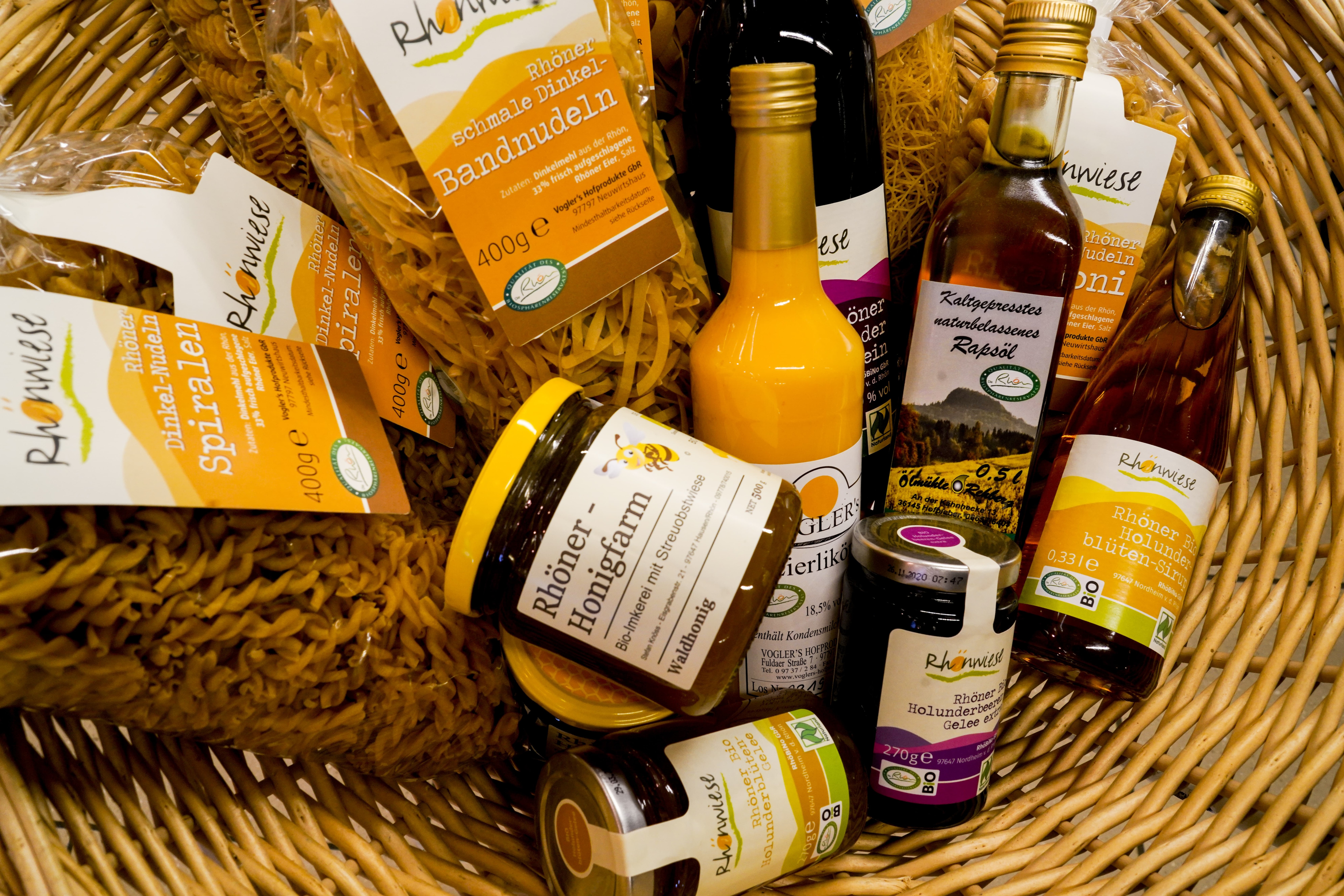 In einem Korb liegen verschiedene regionale Produkte, zum Beispiel Honig und Rapsöl.