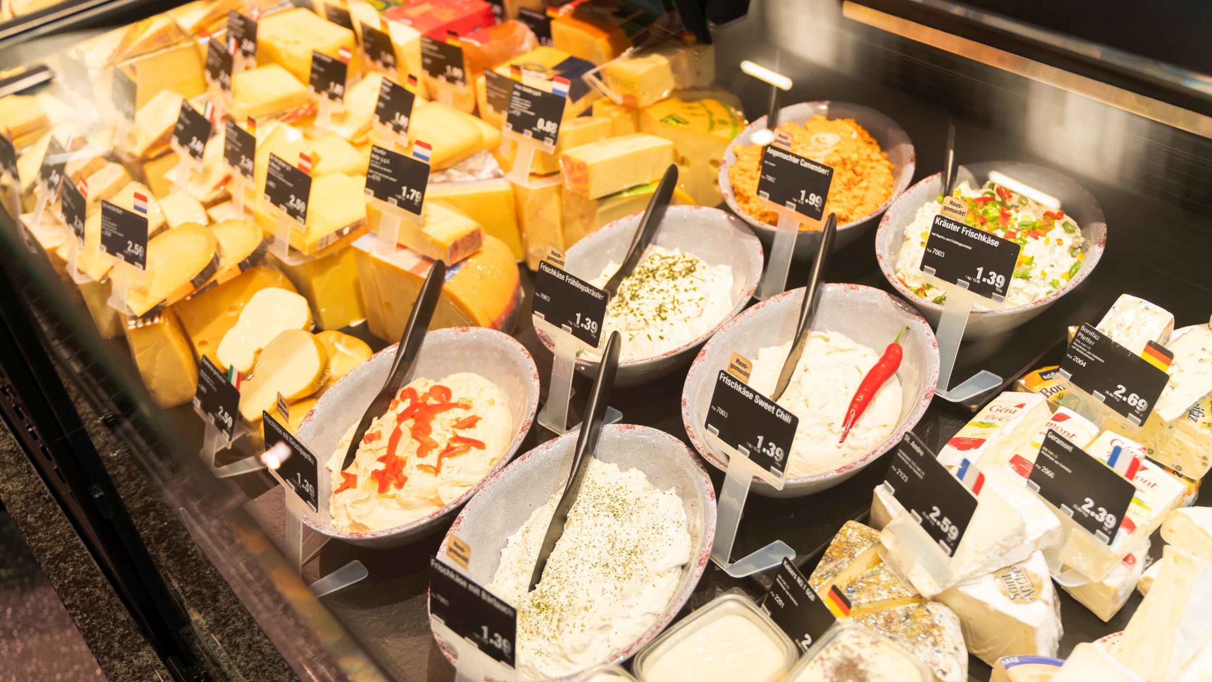 Verschiedene Sorten Block- und Frischkäse in der Auslage der Frische-Bedientheke