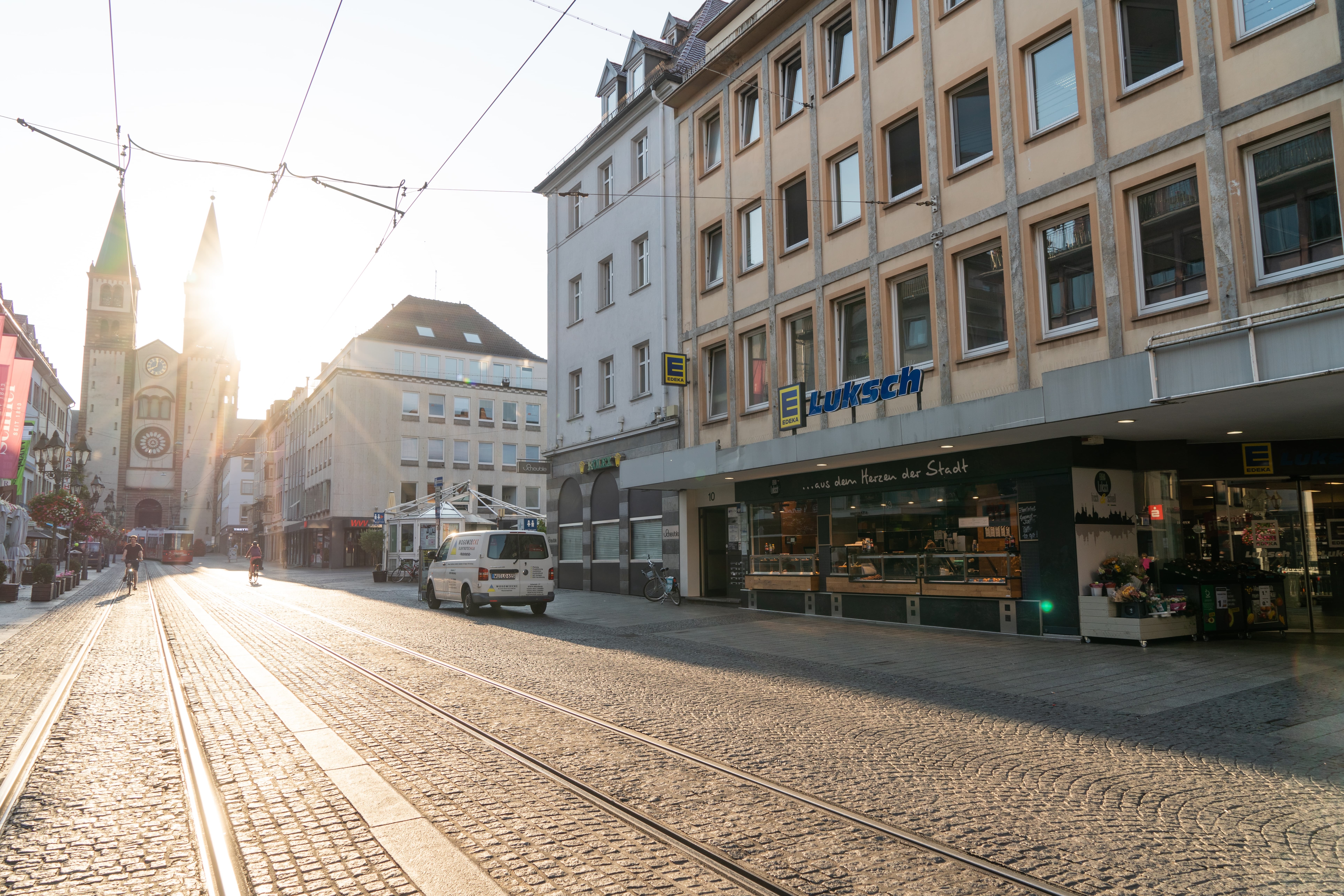Die Außenansicht eines Edeka-Marktes in einer sonnendurchfluteten Innenstadt.