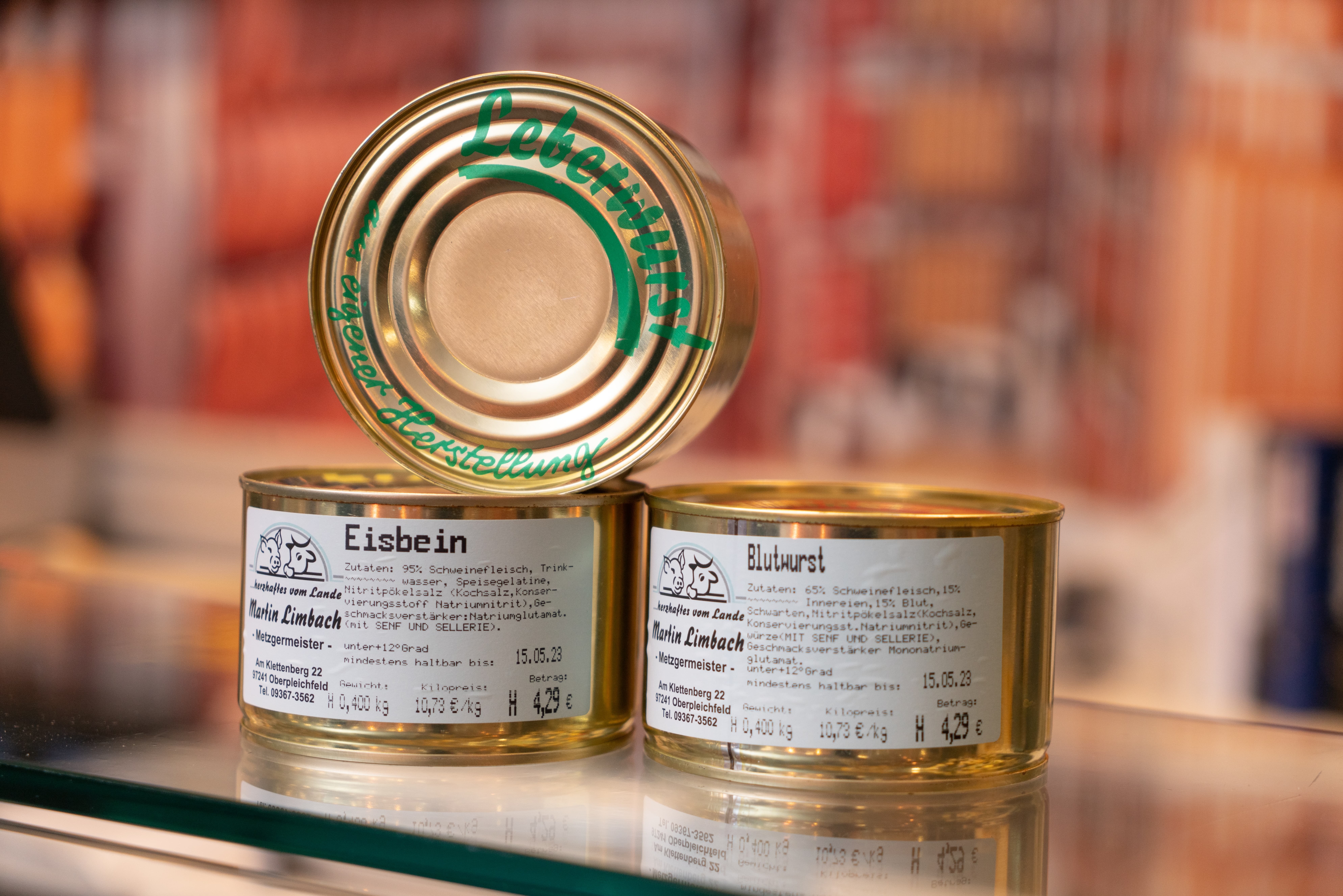 Drei auf einer Theke gestapelte Dosen mit Wurstspezialitäten.