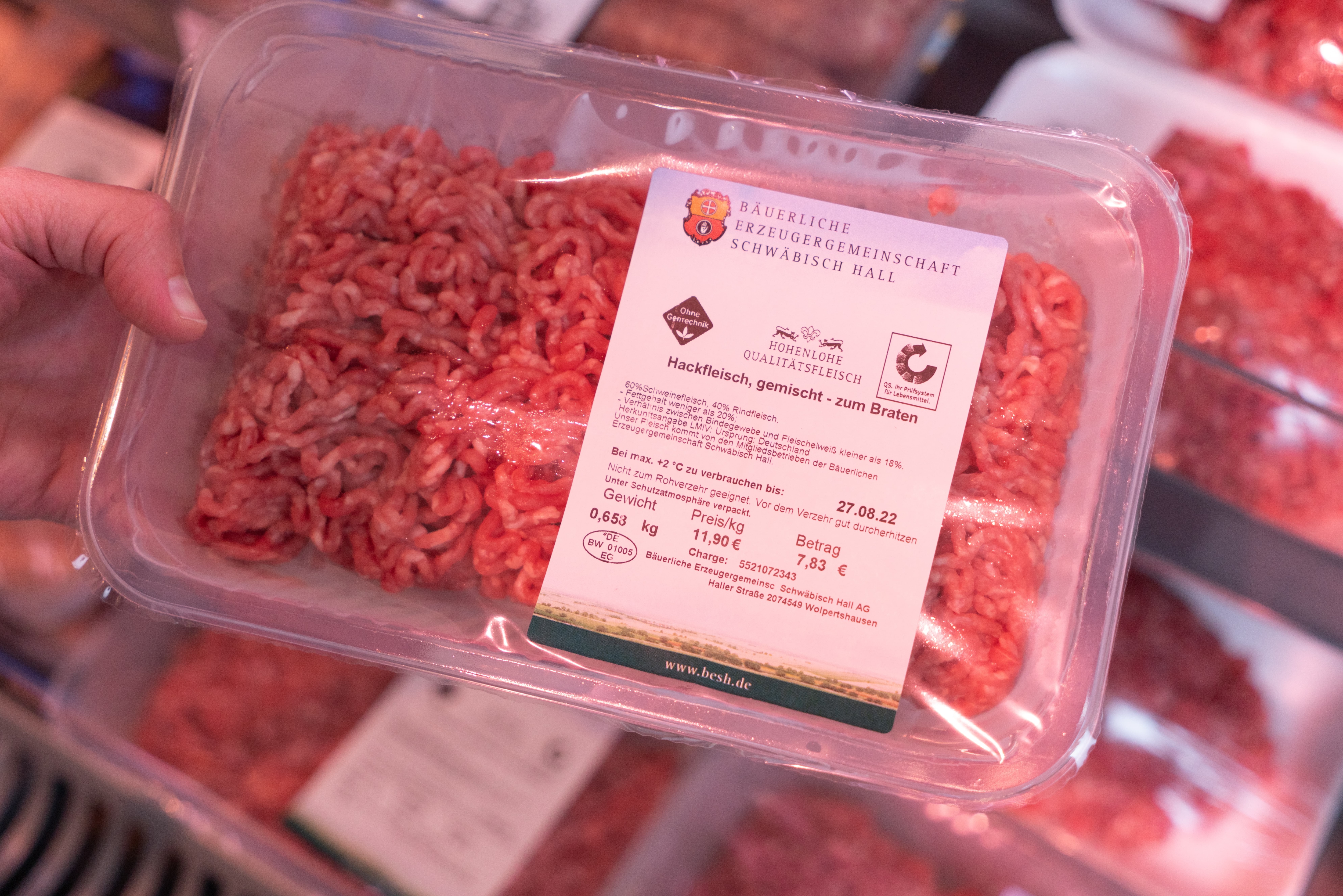 Eine Hand hält ein Paket gemischtes Hackfleisch.