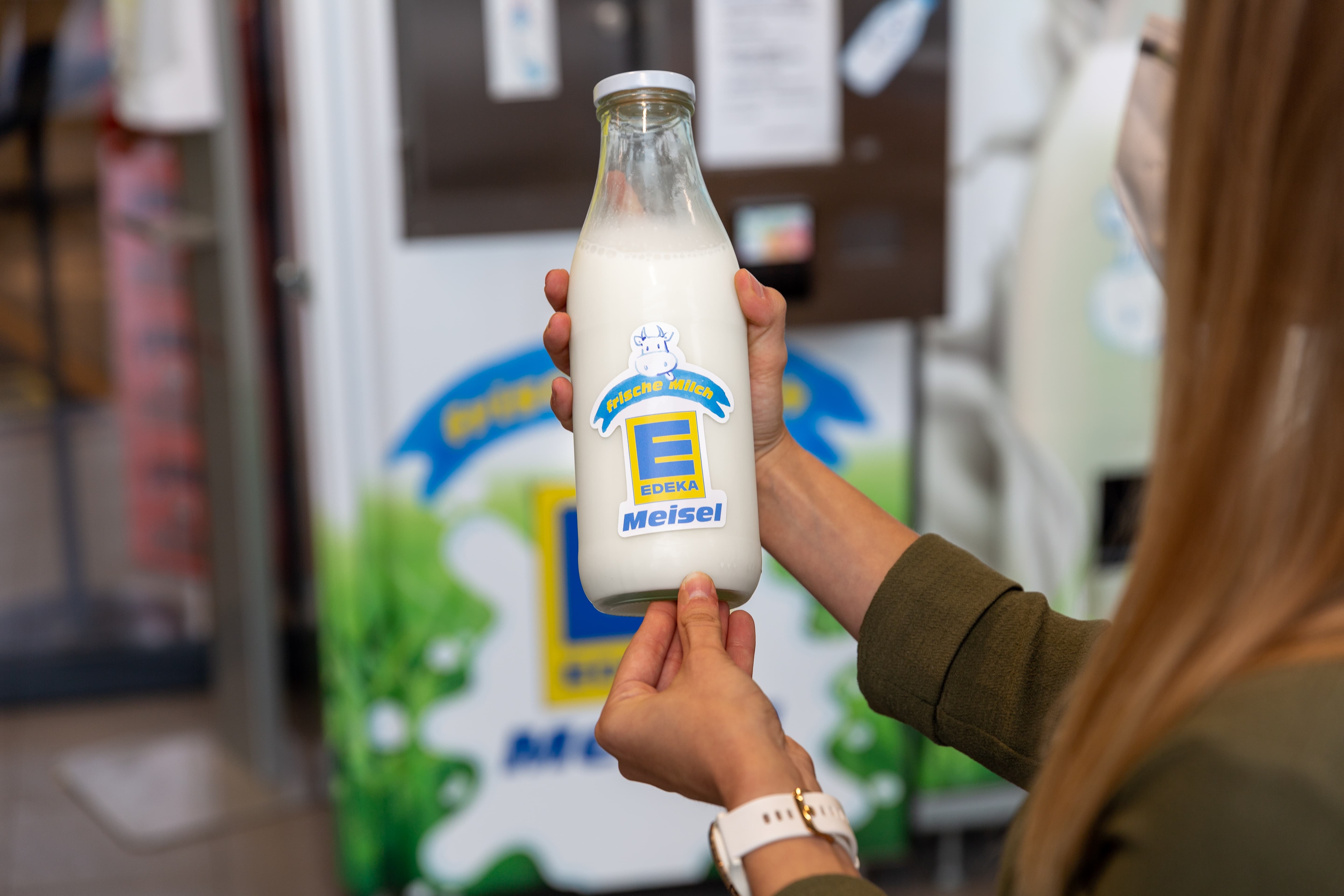 Eine Frau hält eine Flasche der hauseigenen Milch eines Edeka-Marktes in den Händen.