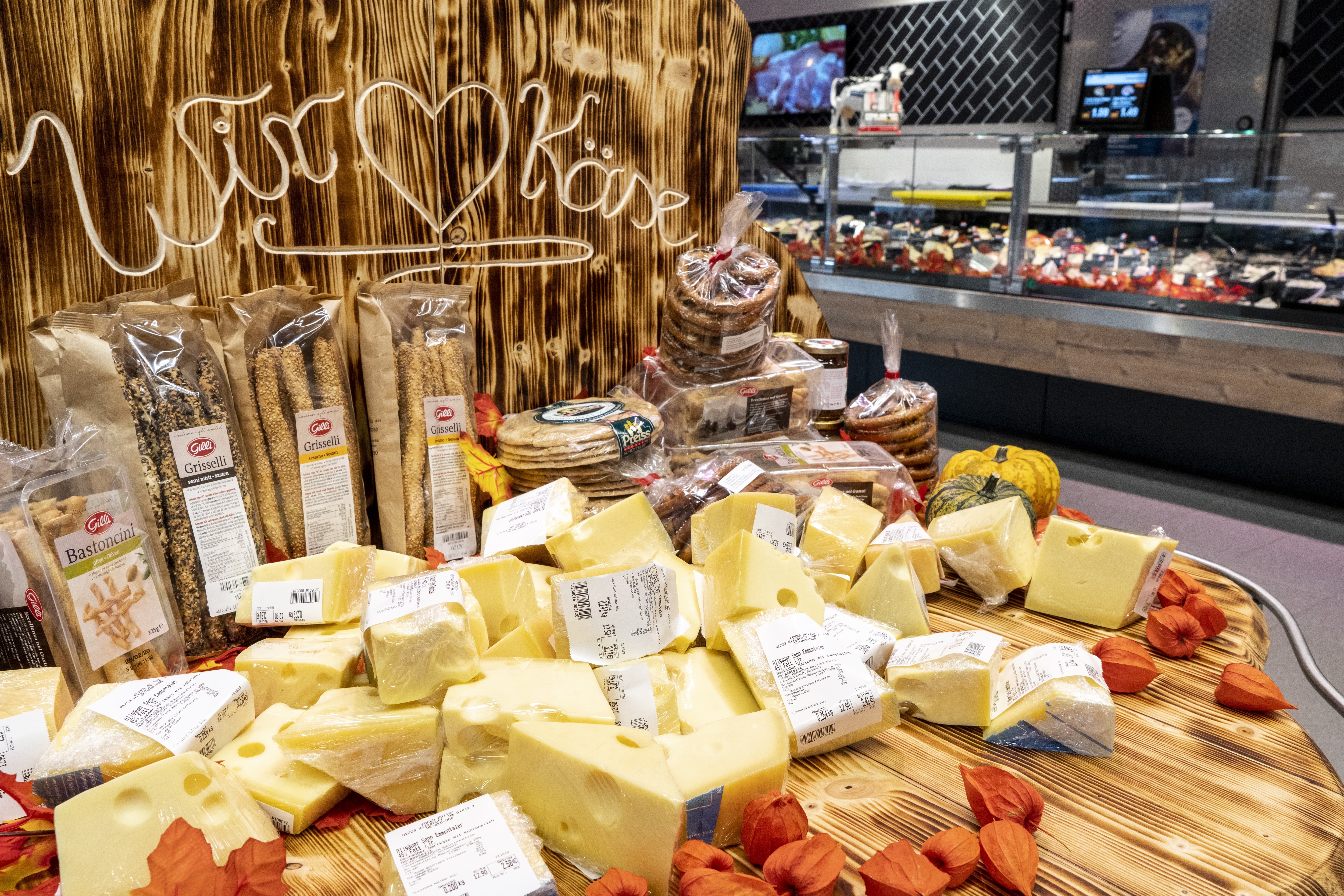 Abgepackter Käse und Grissini auf einer Holzfläche.