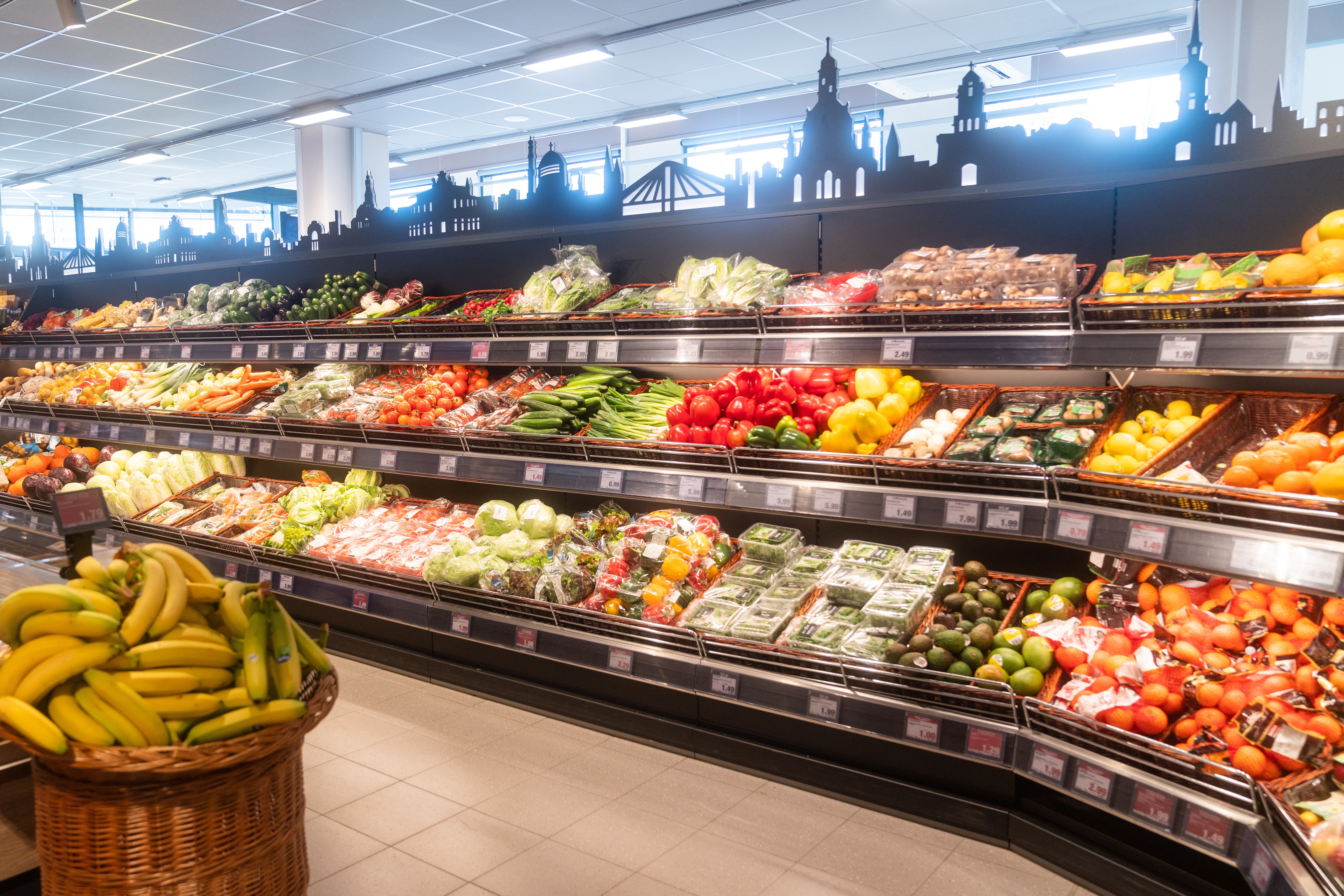Lange Gemüseregale mit einer Skyline über dem obersten Regal.