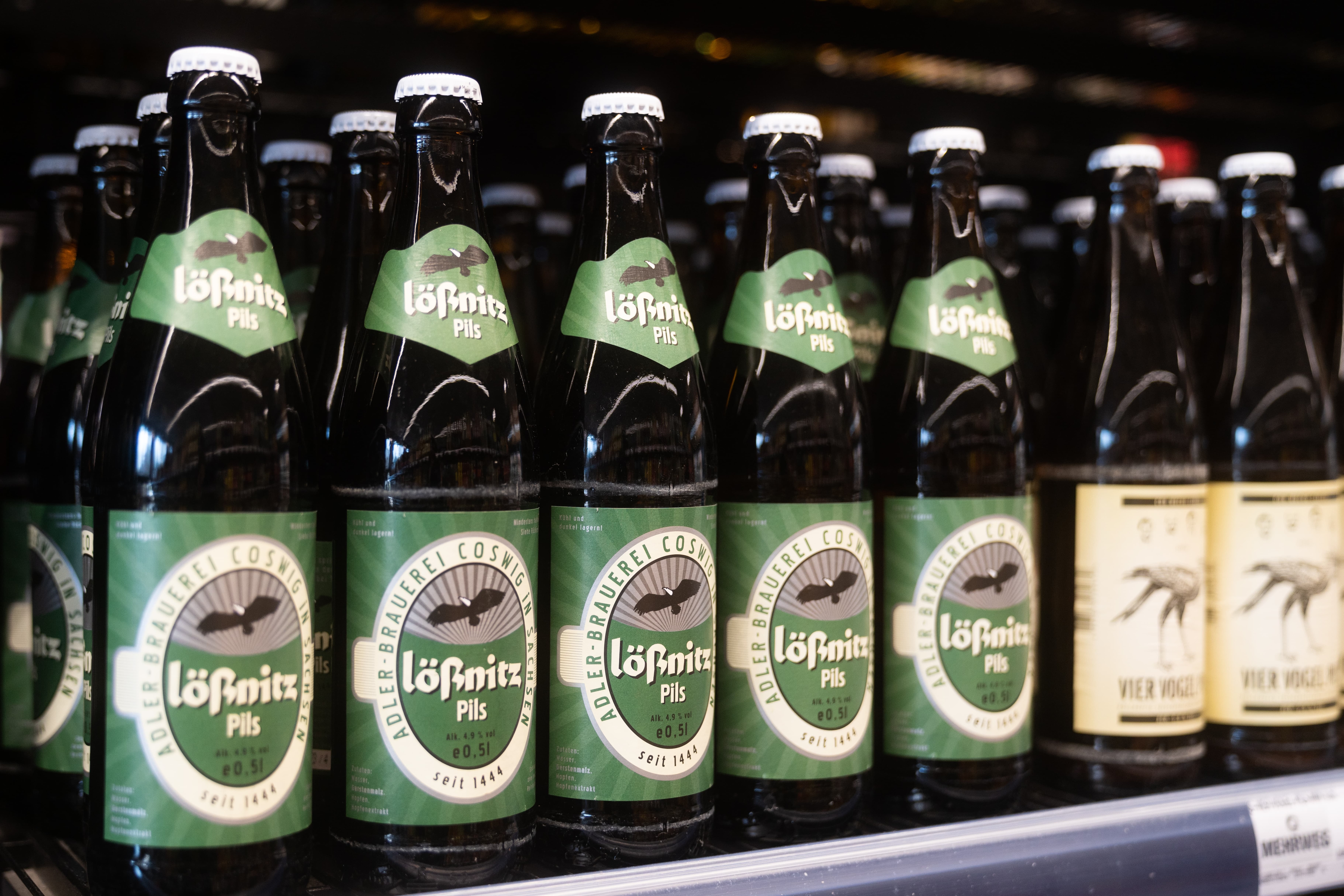 Nahaufnahme von grünen Bierflaschen der Marke Lößnitz Pils in einem Regal.