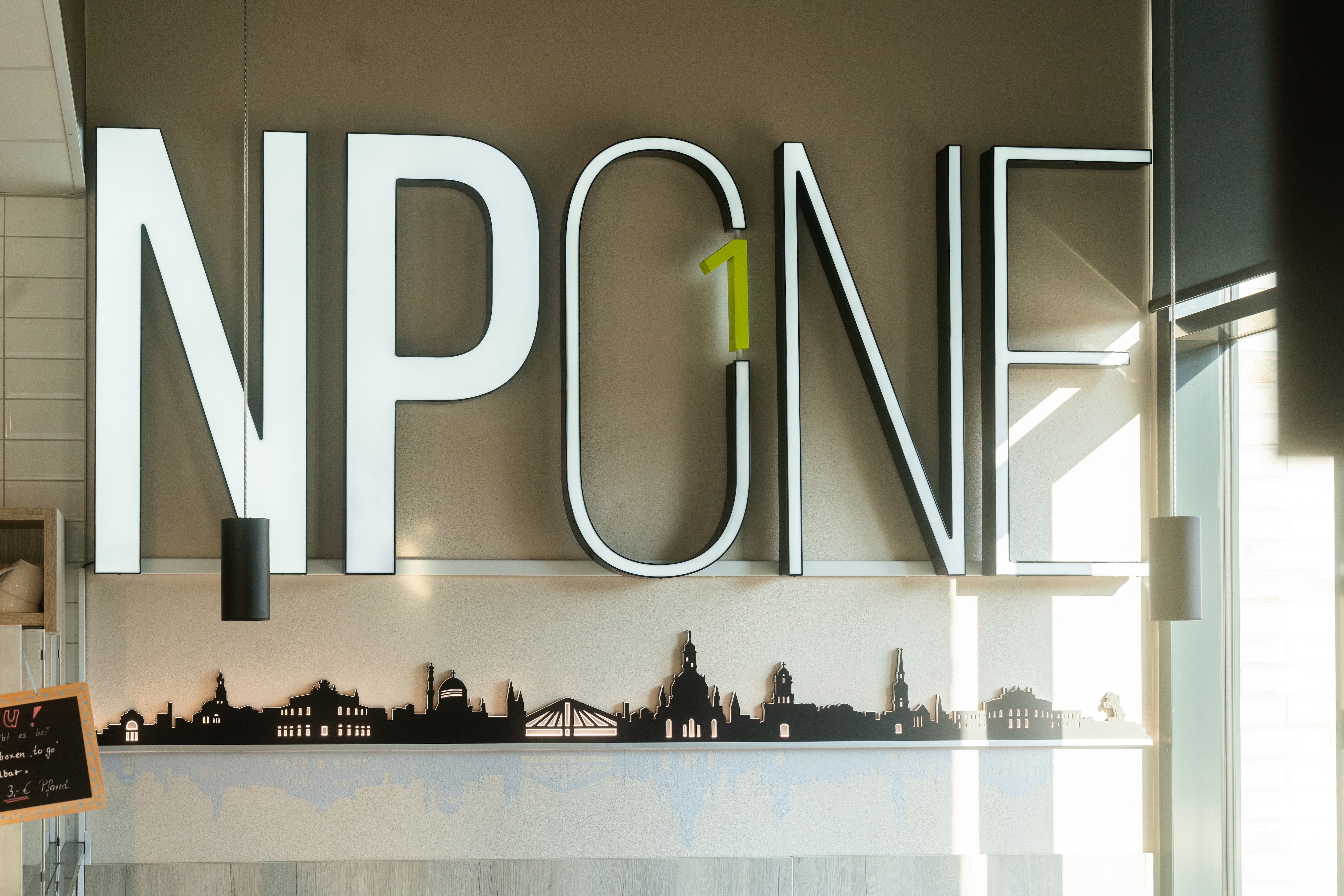 Großes beleuchtetes Logo von NPONE an einer Wand.