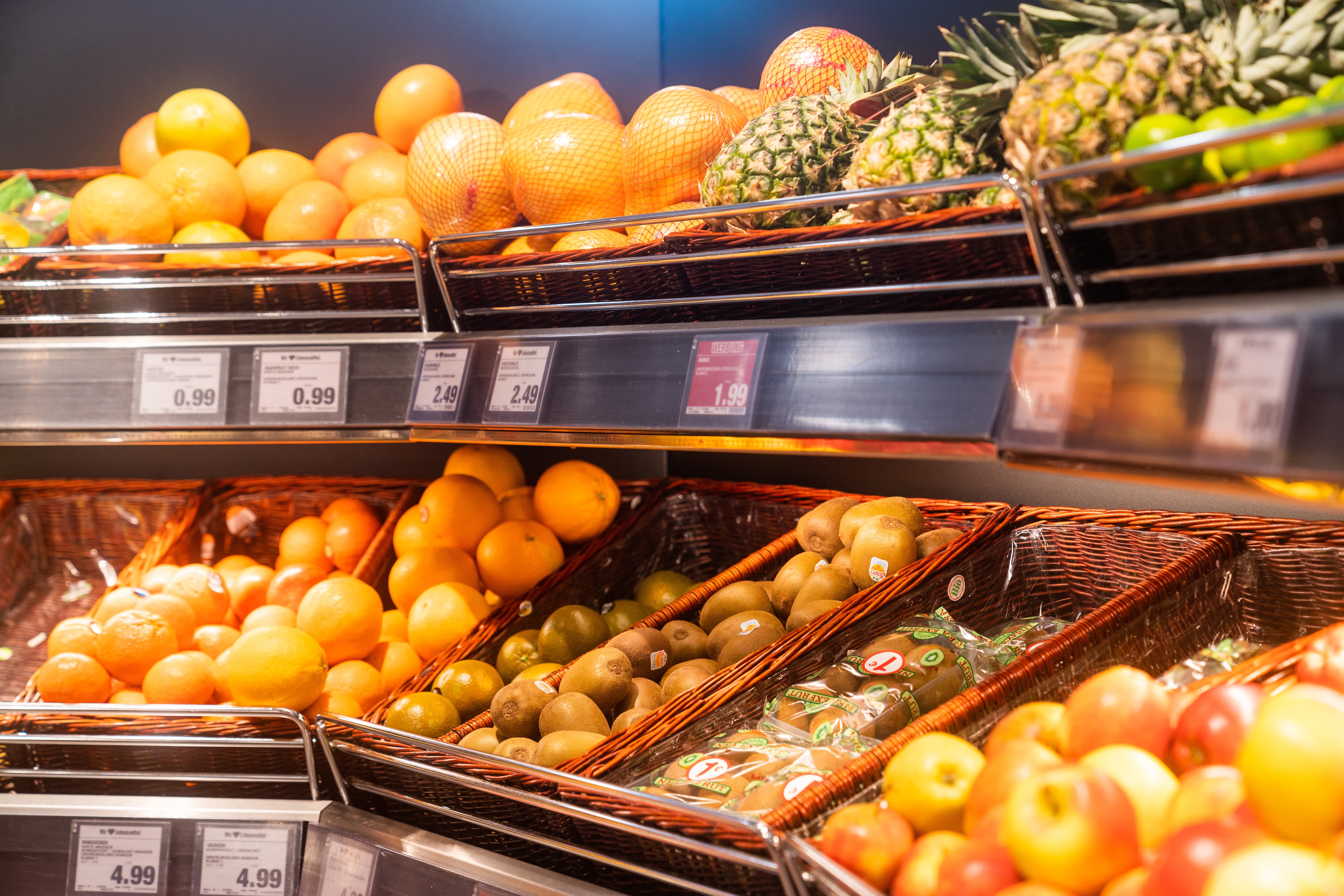 Ein Regal mit Äpfeln und Zitrusfrüchten.