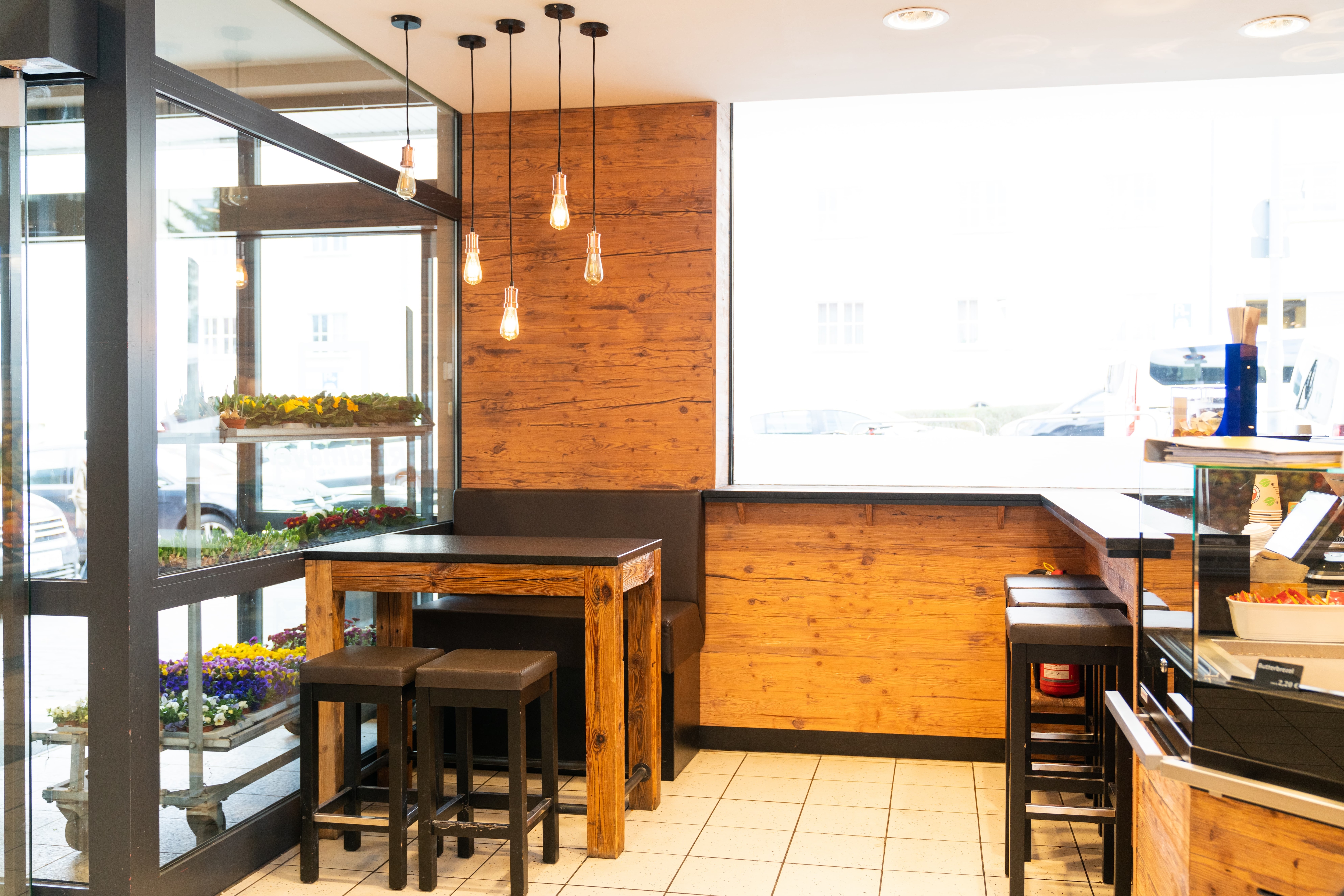 Zwei Hocker und eine Bank stehen an einem viereckigen Holztisch.