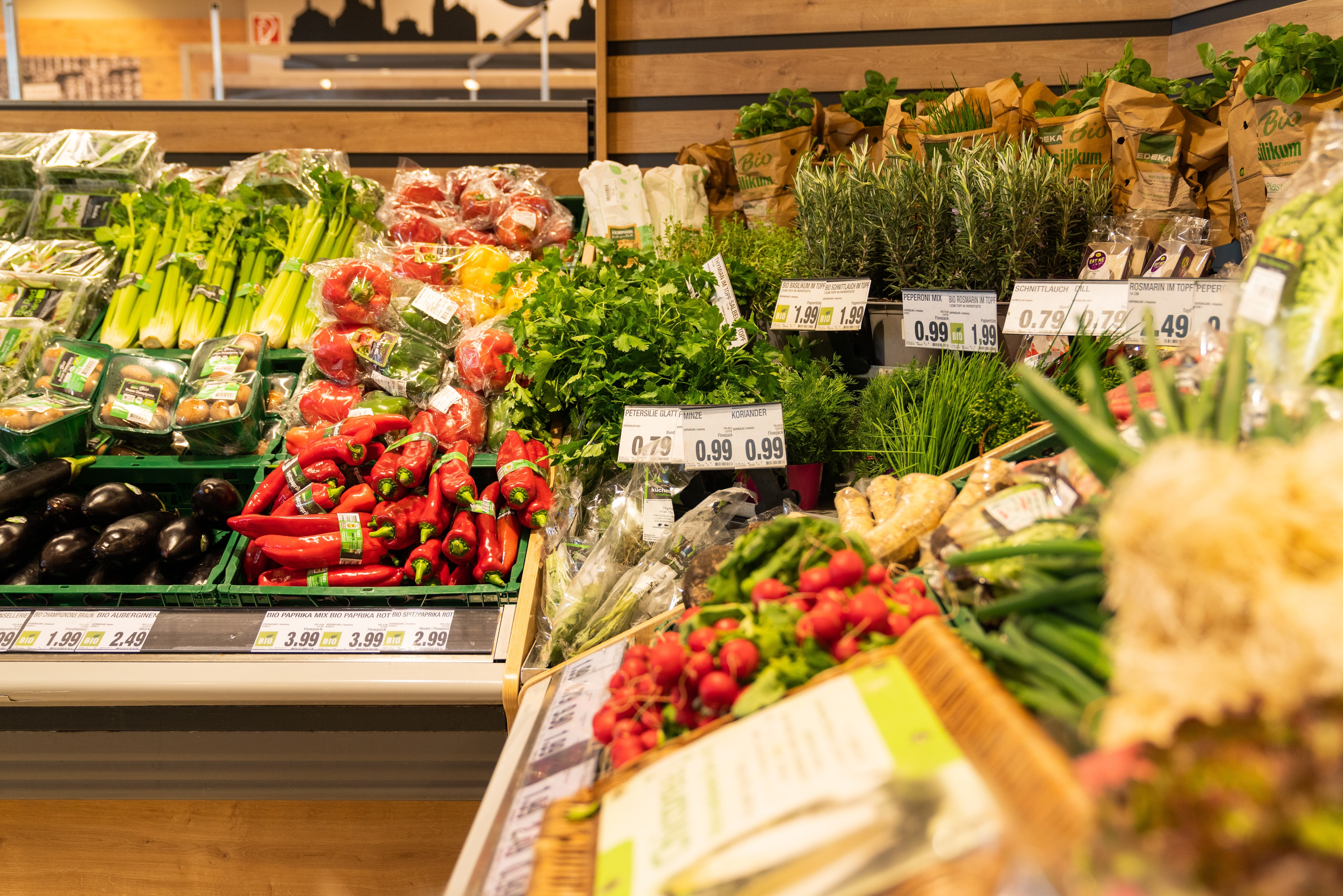 Gemüse und Kräuter in den Regalen des EDEKA-Marktes.