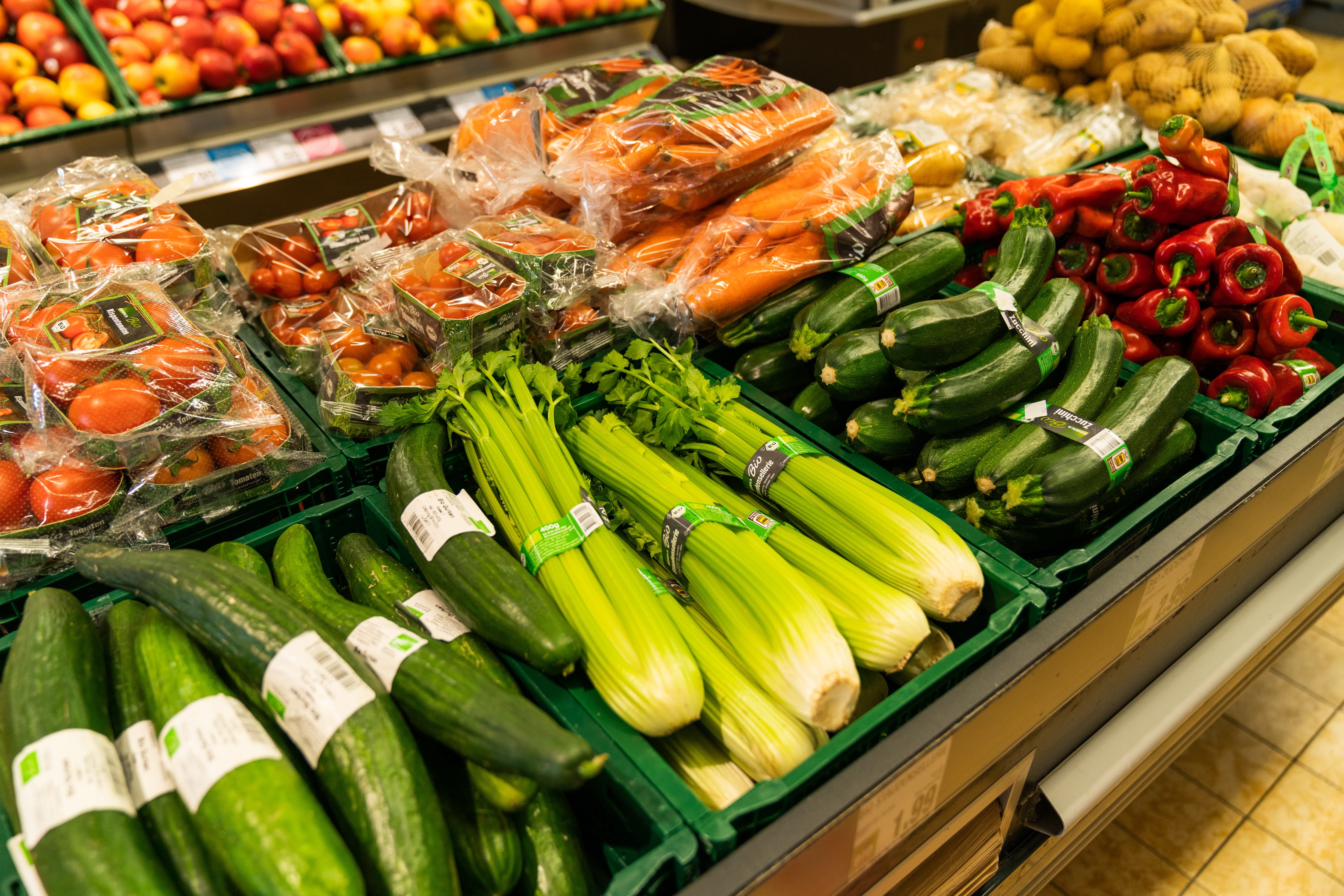 Grüne Kisten mit Gurken, Staudensellerie, Zucchini und Spitzpaprika.