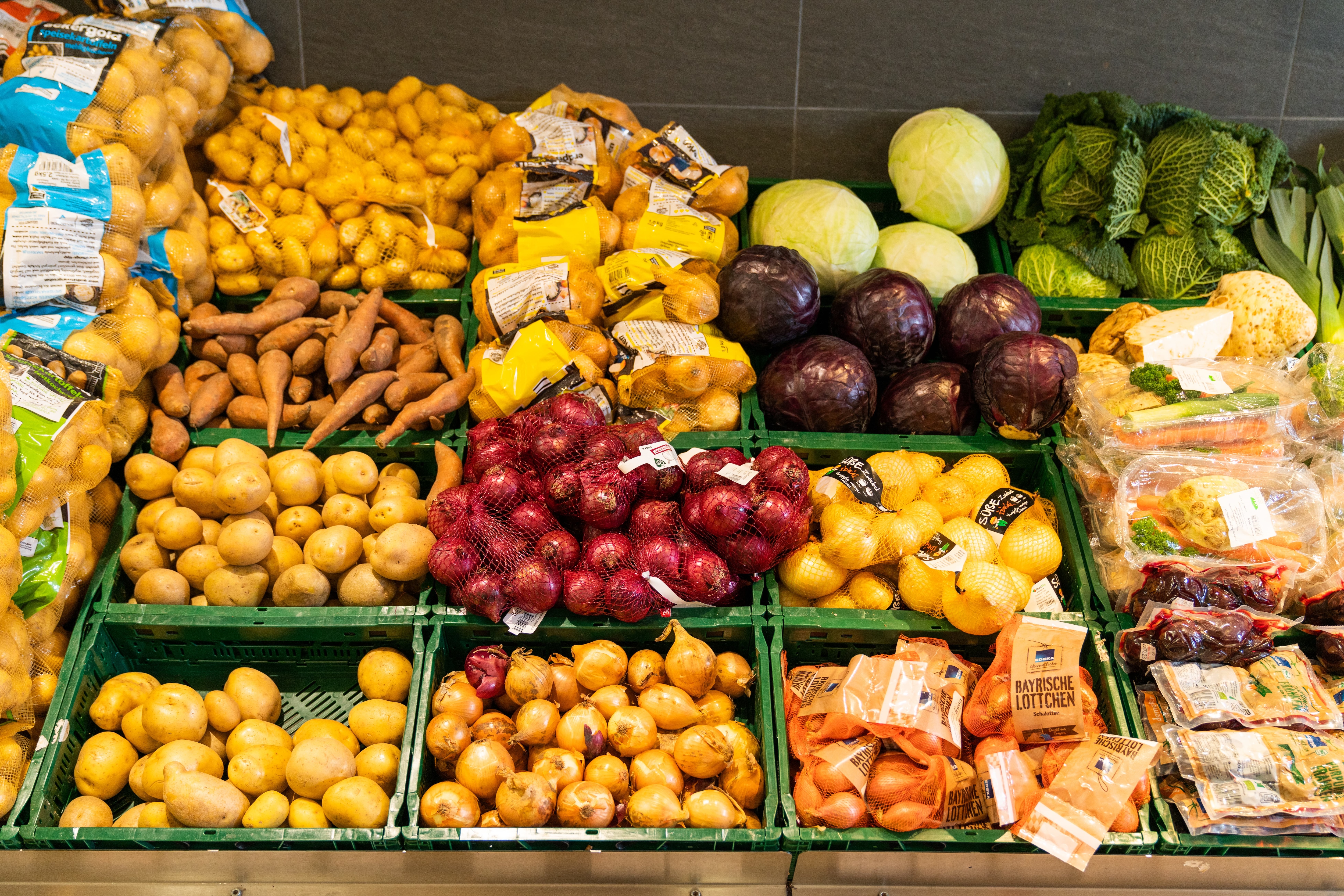 Kartoffeln, Zwiebeln und Kohl in grünen Kisten.